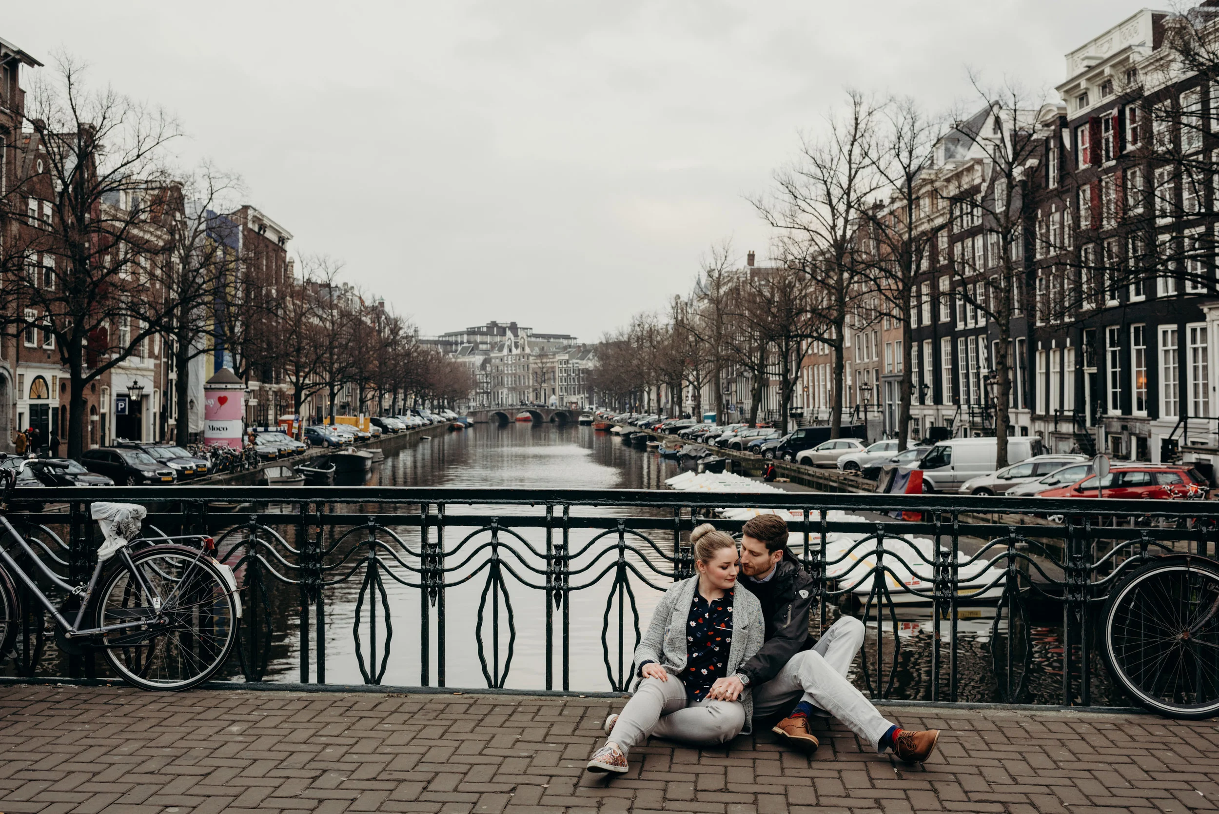 newly married couple sitting on bridge over river in Amsterdam
