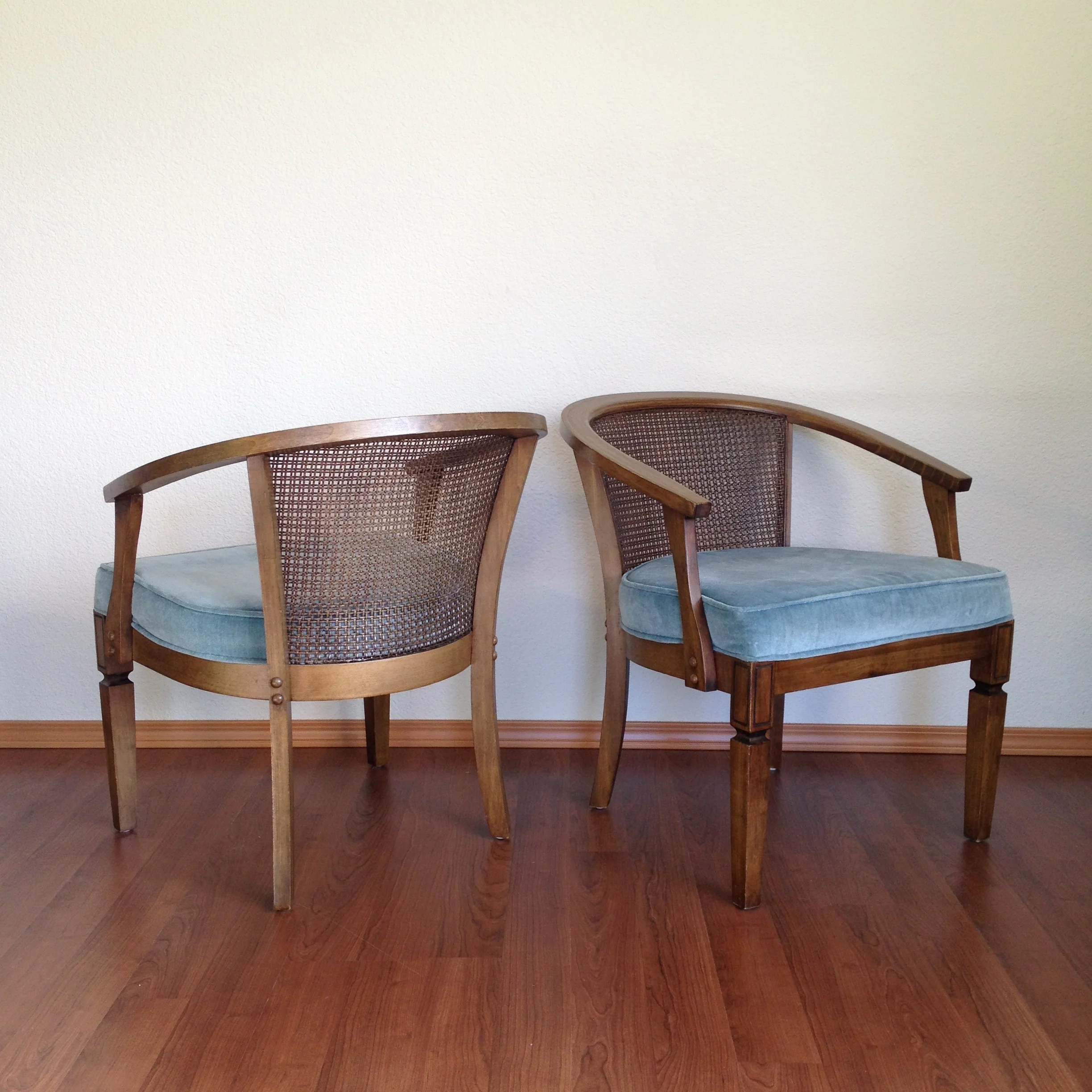pair of vintage cane back chairs with blue upholstered seats.