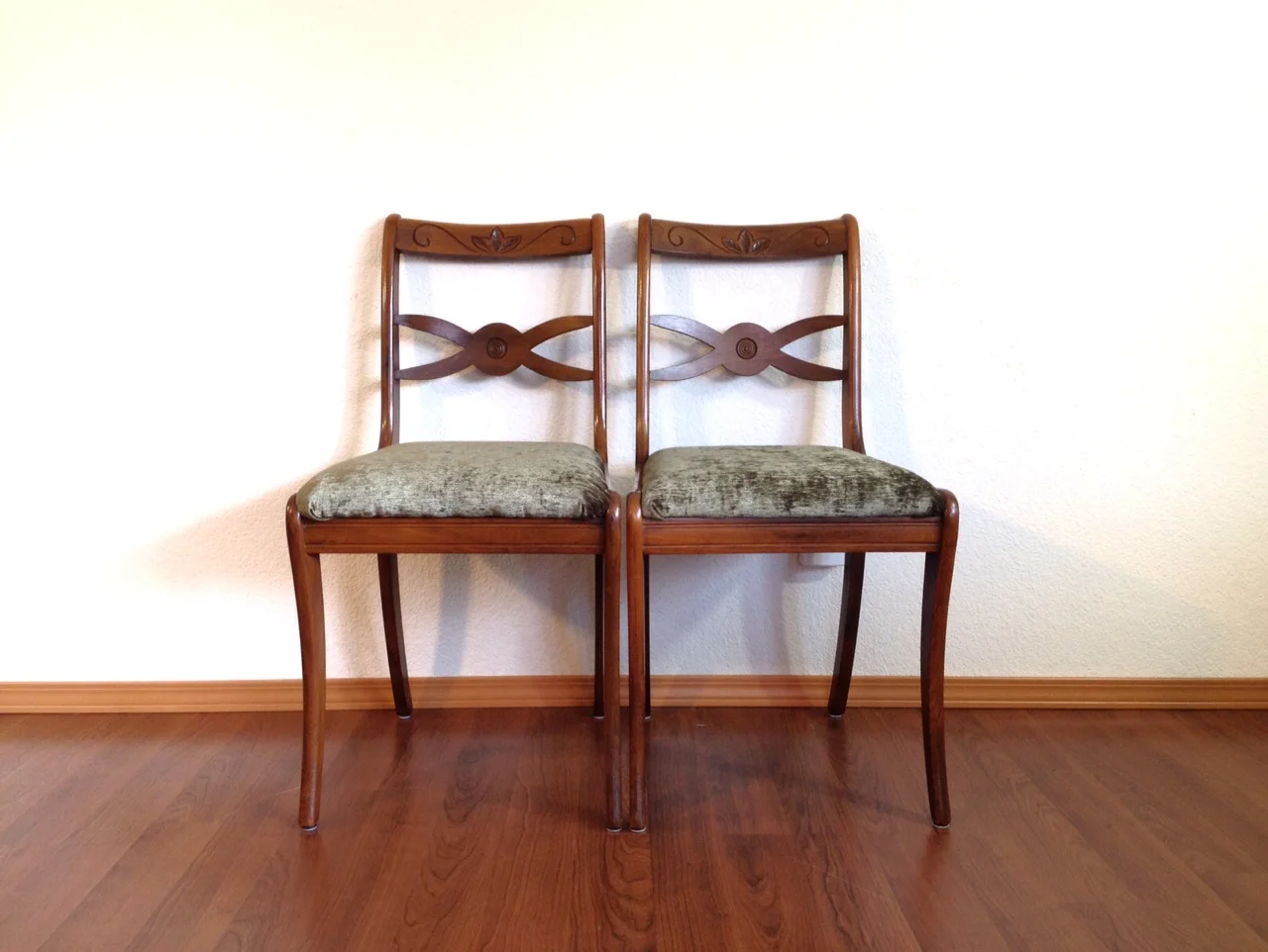 pair of vintage dining chairs with green velvet seats.