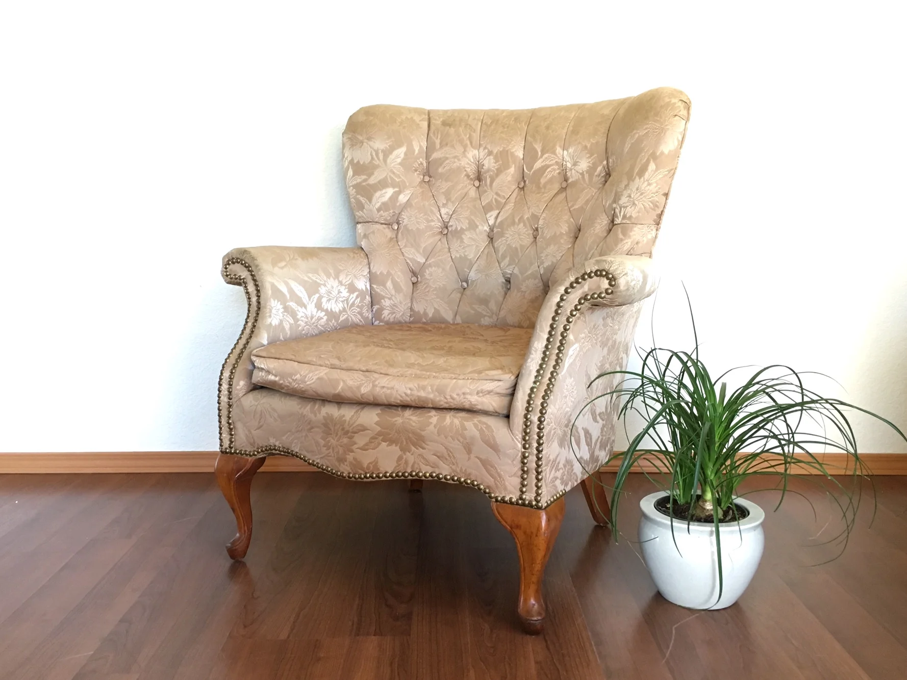 vintage tufted wingback chair in gold upholstery.