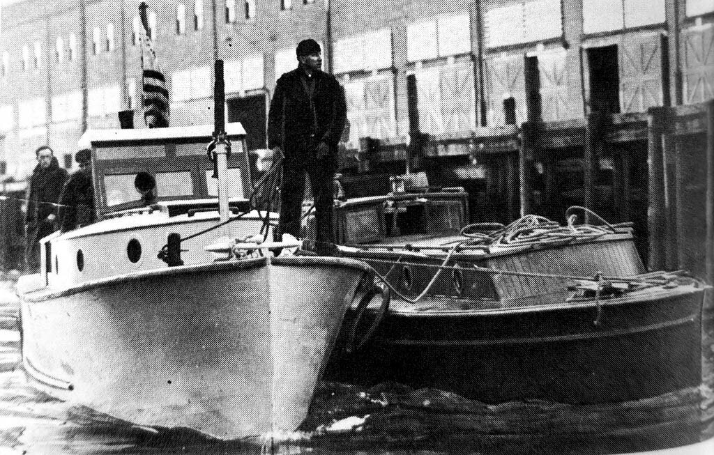 Puget-Sound-Coast-Guardsman-standing-with-captured-rumrunning-boat-1920s.jpg