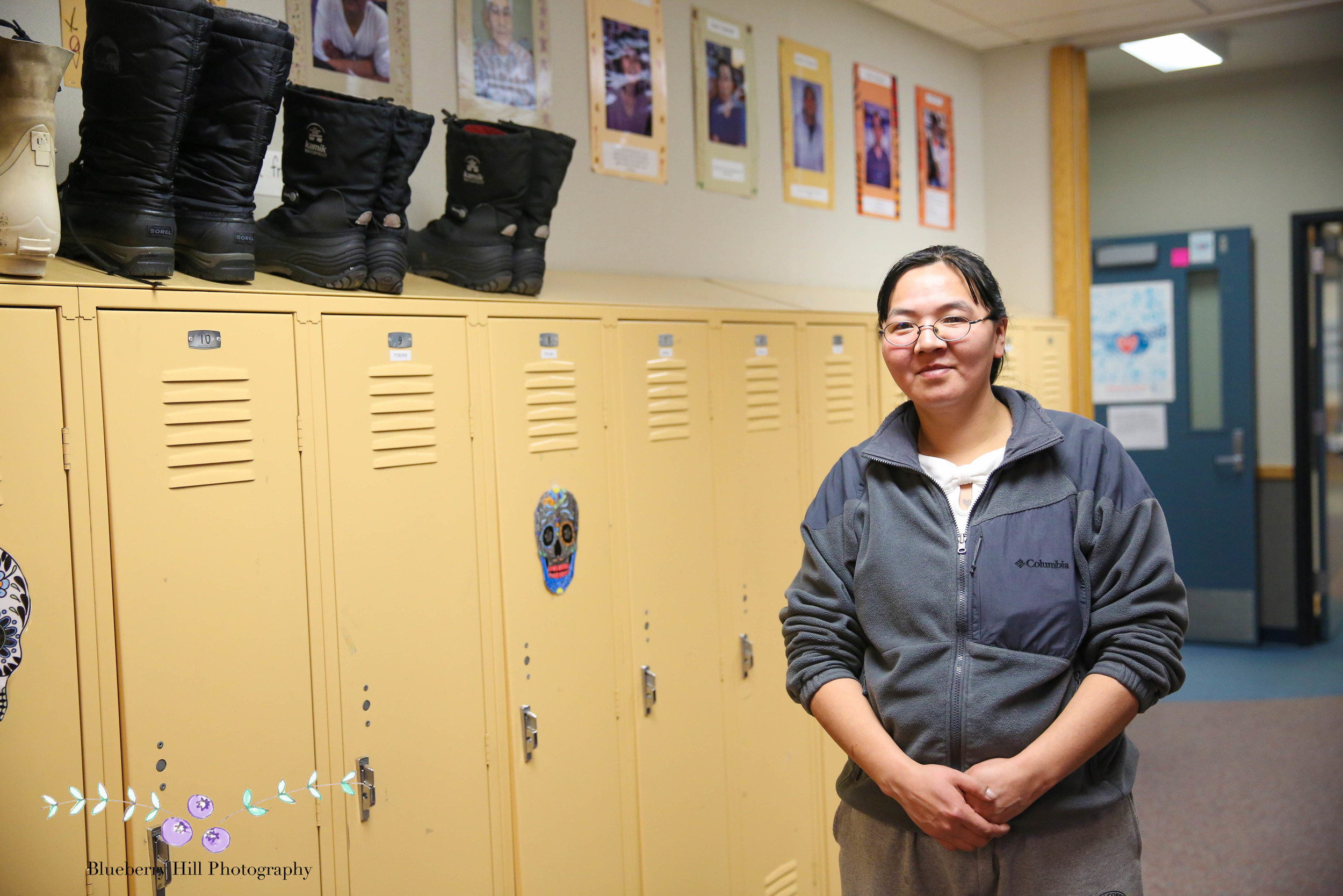 Marie gives me a tour of the school. In the high school wing, heavy-duty snow boots sit atop the lockers. Marie points out all the photos of the elders and young elders hanging in the school.
