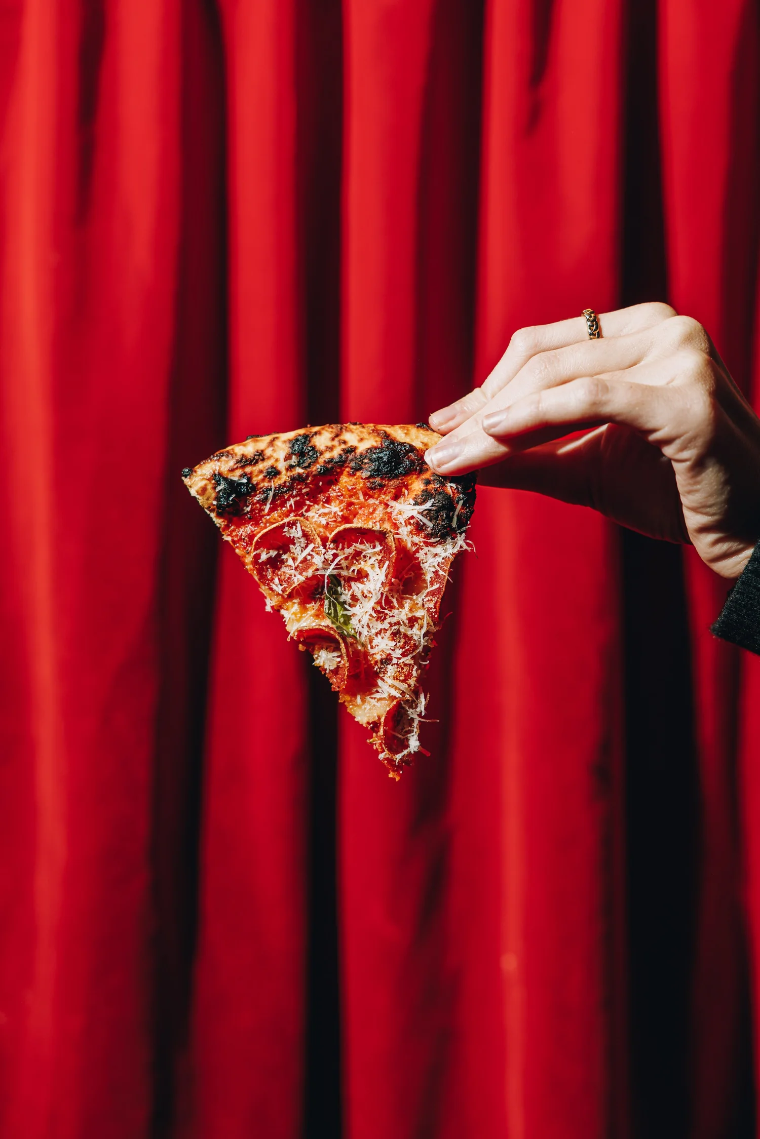 Devoured pizza photographed against a red curtain