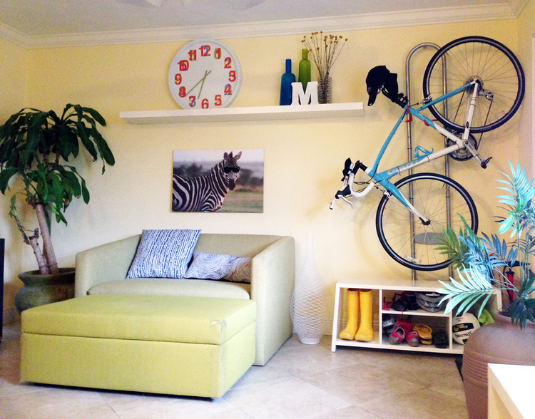 Living Room This also functions as a guest room when I have a visitor since the ottoman stores extra linens and the couch folds out into a bed. Hanging my bike horizontally instead of vertically saves space and the cubbies below keep sports stuff organized. I created the zebra art myself. The wire vase adds some style without seeming bulky. And you'd probably guess that plant in the lower right corner is fake - but would you guess it's actually a litter box? 
