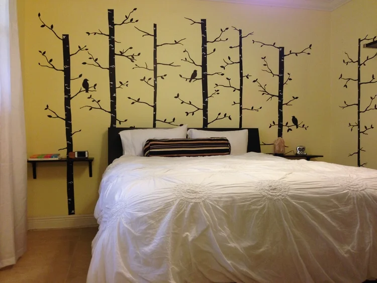 The Bedroom I wanted something whimsical that I would love waking up to each morning so I went with a slightly enchanted forest theme. The headboard has storage compartments for housing chargers and books and mounting shelves on the wall instead of using side tables makes the space feel larger and less cluttered. I love bright, white hotel-style bedding so I opted for a subtle, white, flower-embroidered duvet that wouldn't clash with the busier wall design. 