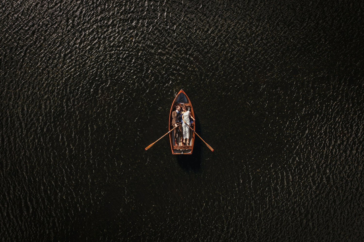A couple in a row boat at their wedding photographed by a drone from above