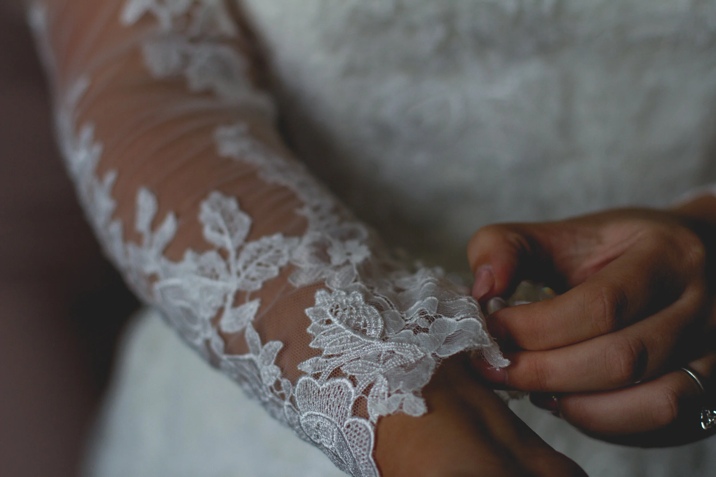 close up of bride doing her dress sleeves up showing off her lovely lace sleeves Liverpool Wedding Photographer.  