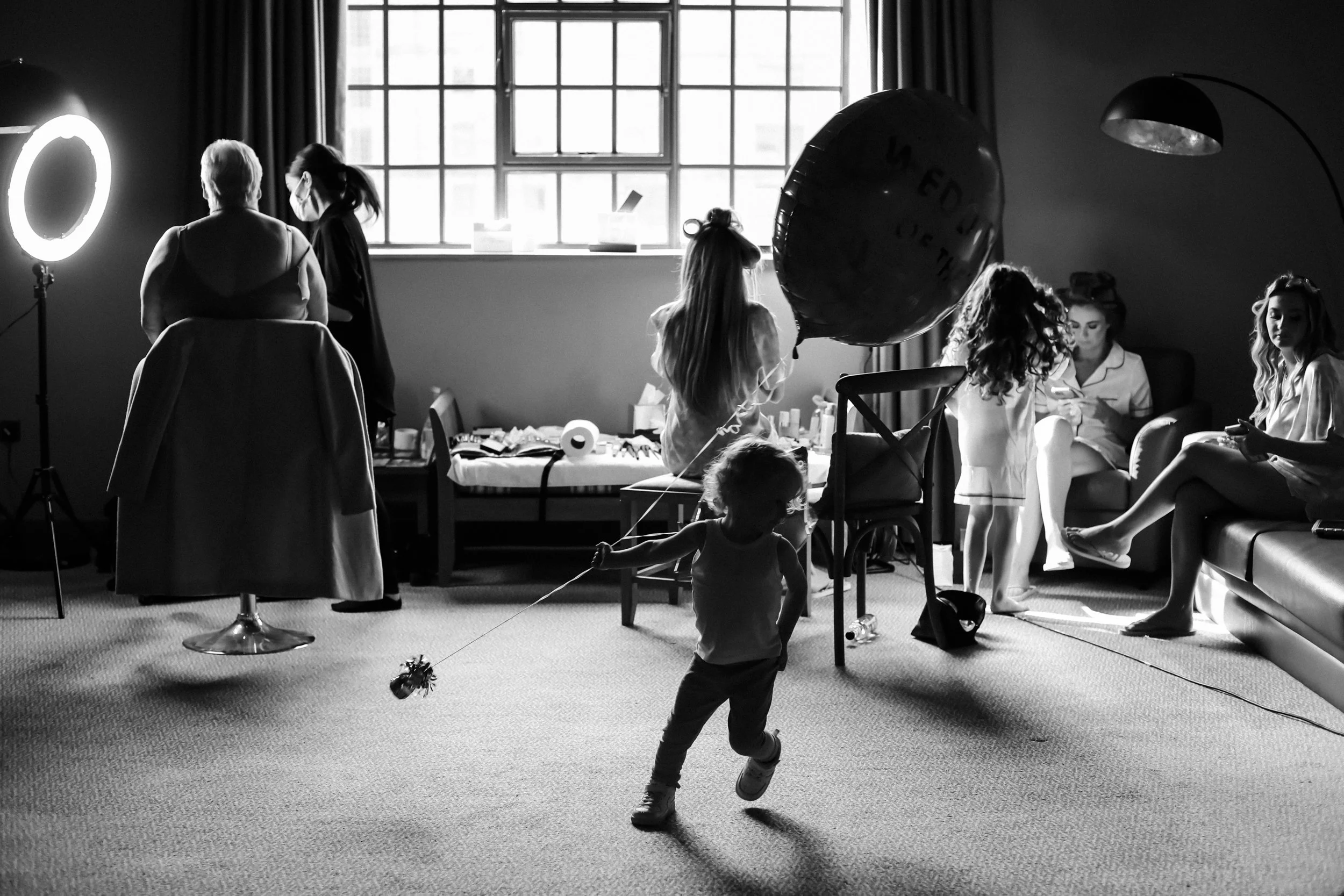 Wedding Morning Harmony: In the Calm Atmosphere of Titanic Hotel, the Bride, Bridesmaid, and Mother of the Groom Sit Quietly as a Young Boy in the Center Adds a Playful Touch, Dramatically Running Aro