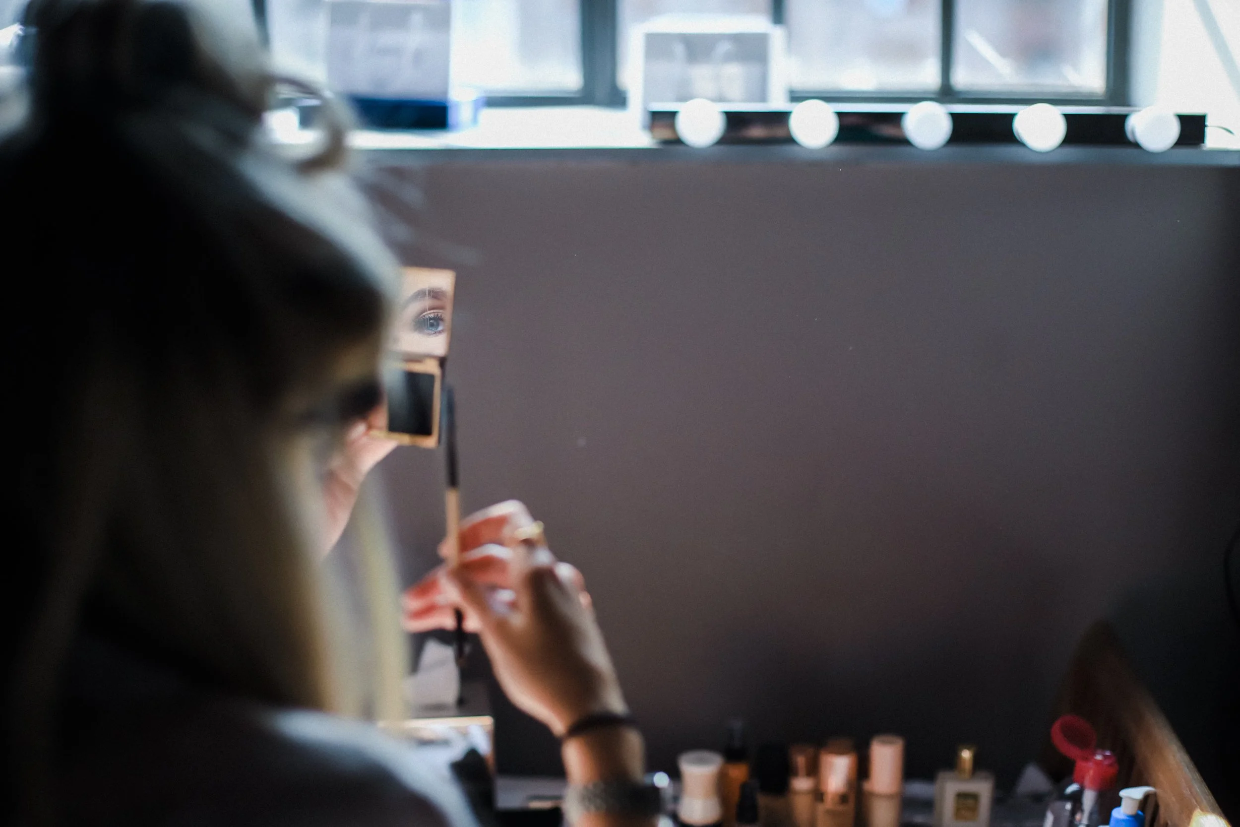 Reflective Gaze: Bridesmaid's Eye Captured in the Mirror During Wedding Morning Preparations, Adding a Unique Perspective to the Scene.