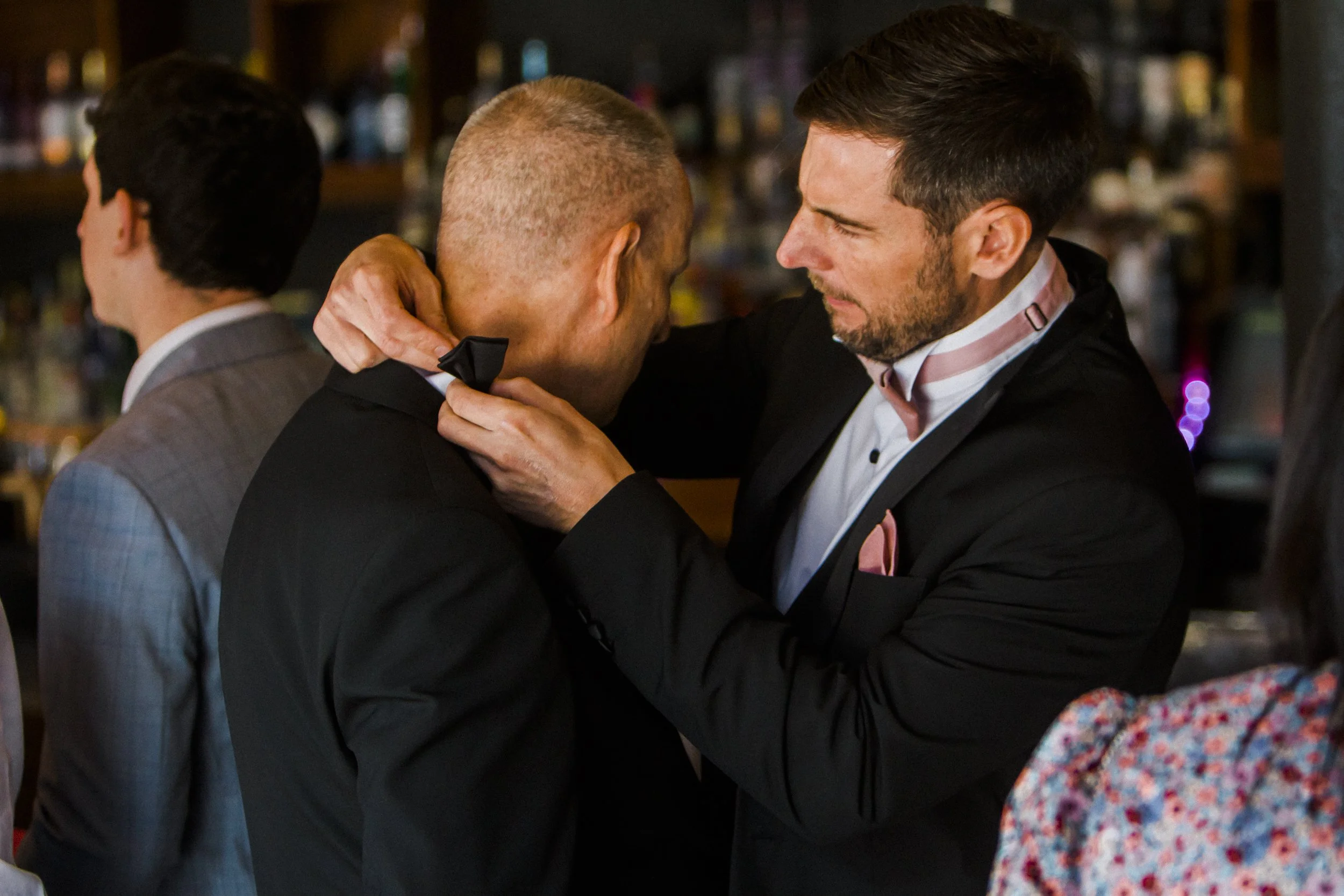 Generational Bond: Groom Assists in Tying His Father's Tie in the Titanic Hotel Lobby, Illustrating a Heartwarming Connection Between Father and Son on This Special Day.