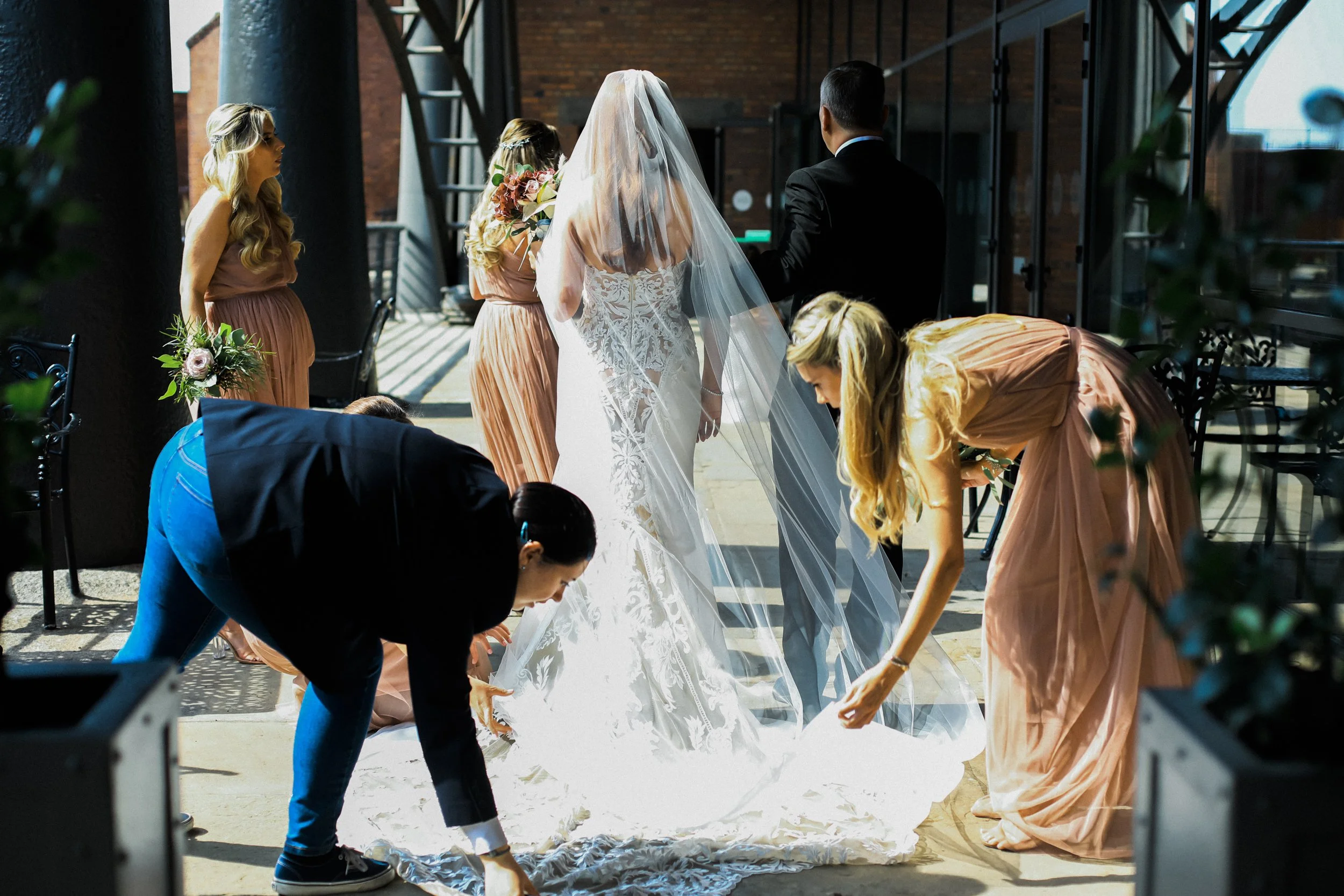 Awaiting the Moment: Bride Stands Outside Titanic Hotel, Eagerly Awaiting Her Walk Down the Aisle, While Her Bridesmaid Offers Support with Her Dress and Veil.