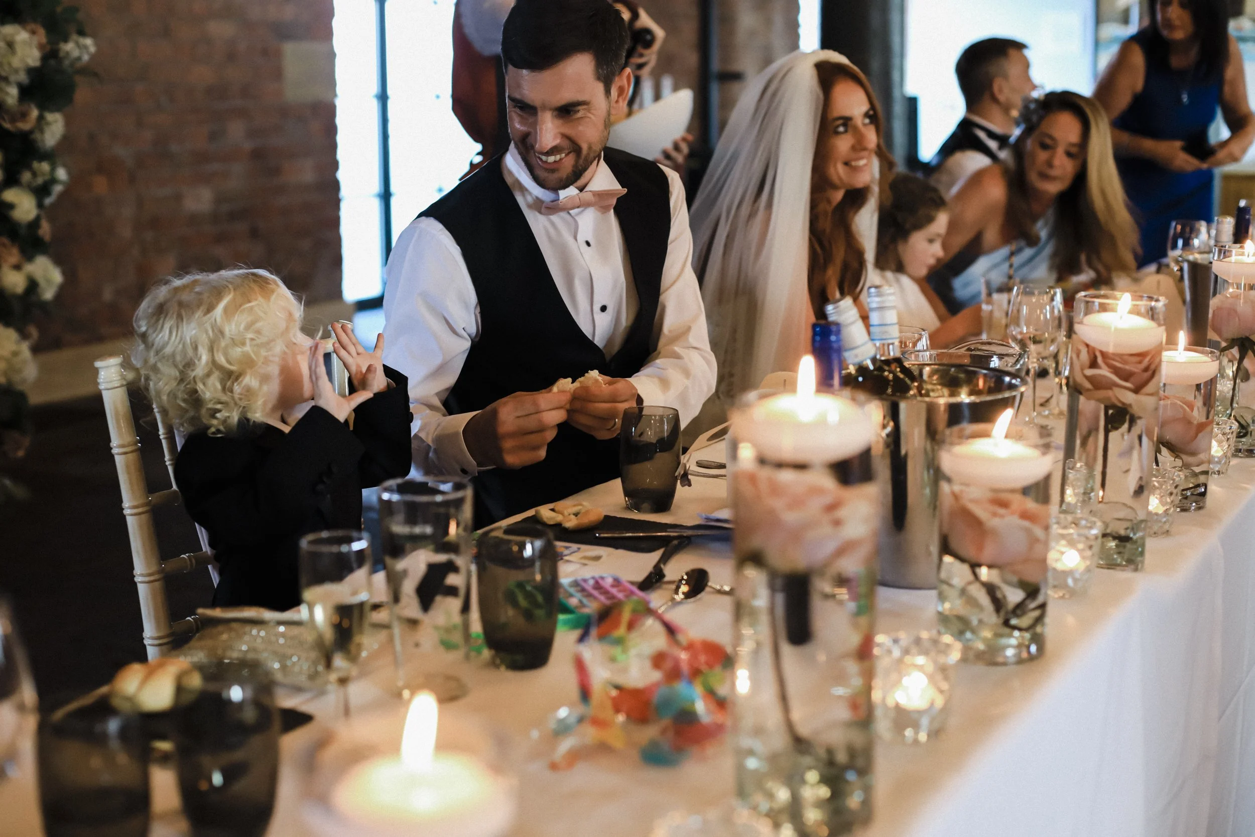 Bonding Moments: Father and Young Son Share Precious Bonding Time at the Wedding Table, Creating Heartwarming Memories on This Special Day.