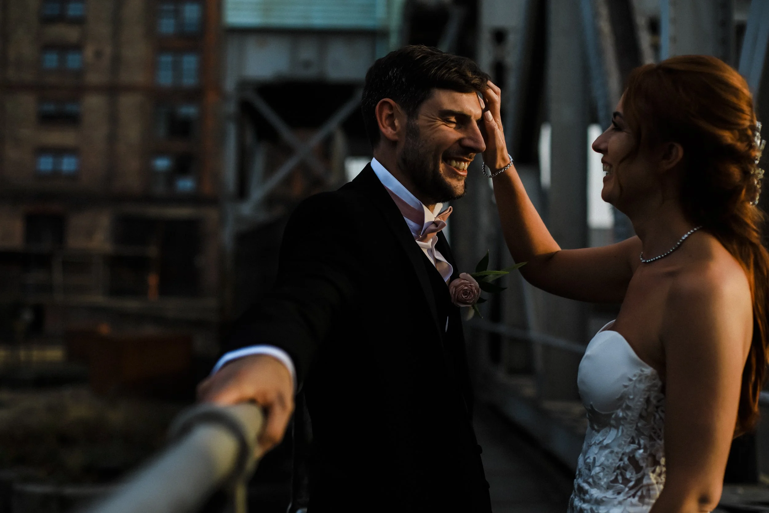 Playful Moment: Candid Shot of the Bride Playfully Messing with the Groom's Hair at Liverpool's Stanley Docks Bridge, Capturing a Light-Hearted and Fun Interaction.