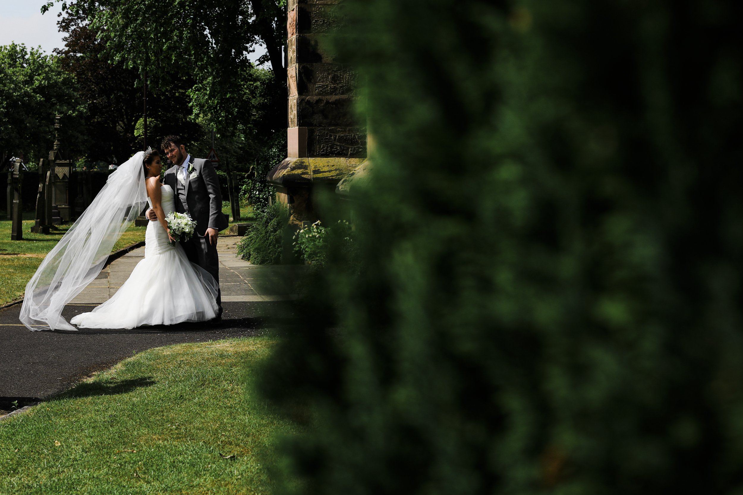 Bride and Groom Pose Amidst the Scenic Grounds of St. Anne's Church in Ormskirk, Capturing the Essence of Their Special Day.