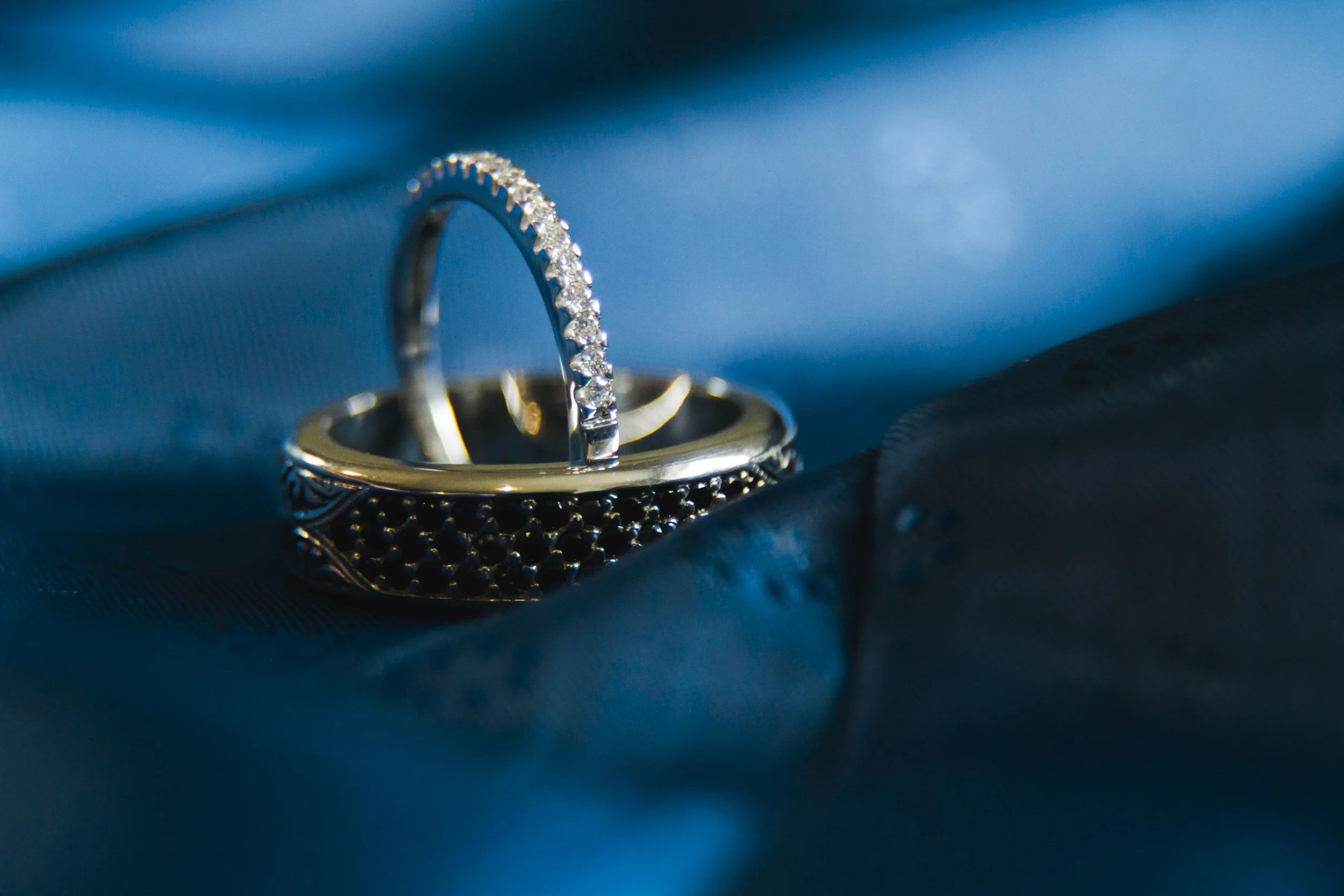 Elegant Details: Close-Up of Bride and Groom's Wedding Rings Resting on a Blue Silk Fabric