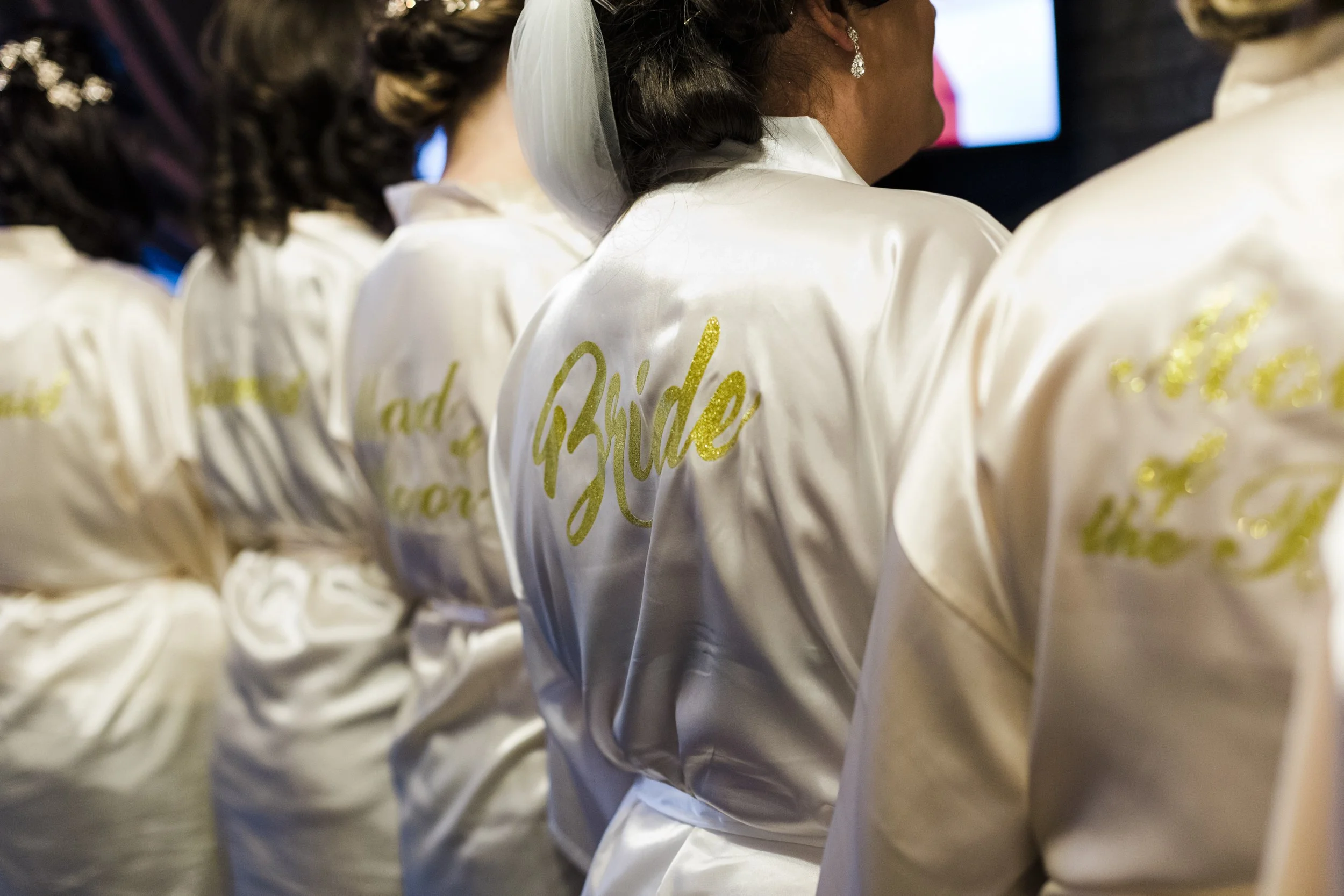 Bride and her bridesmaids, all lined up in their morning dressing gowns, share a joyful moment of anticipation during the wedding preparations for a charming Wirral winter wedding."