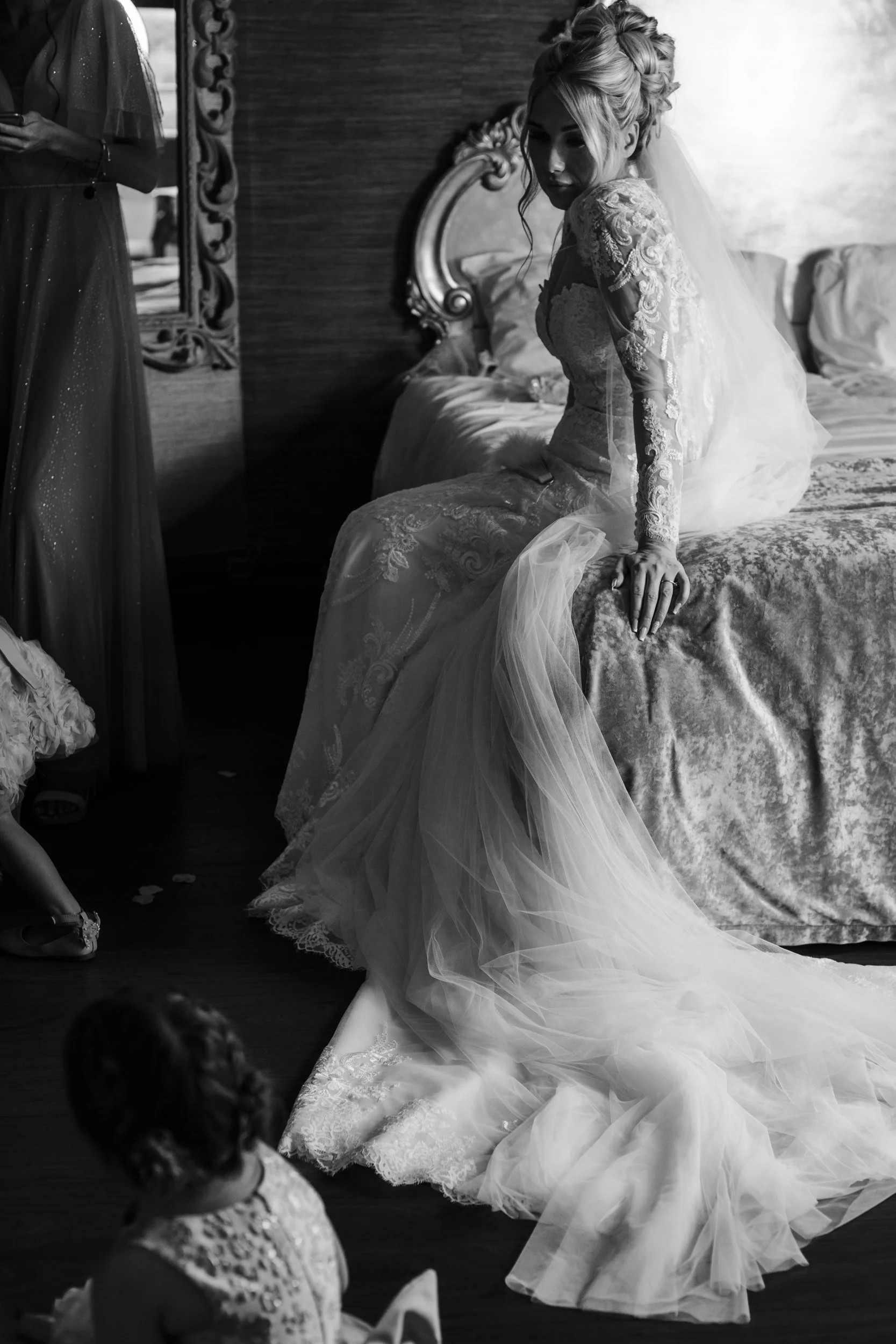 Bride, Eagerly Awaiting Her Descent to the Ceremony, Gracefully Sits on the Bed with Her Dress and Veil at Shankly Hotel Wedding
