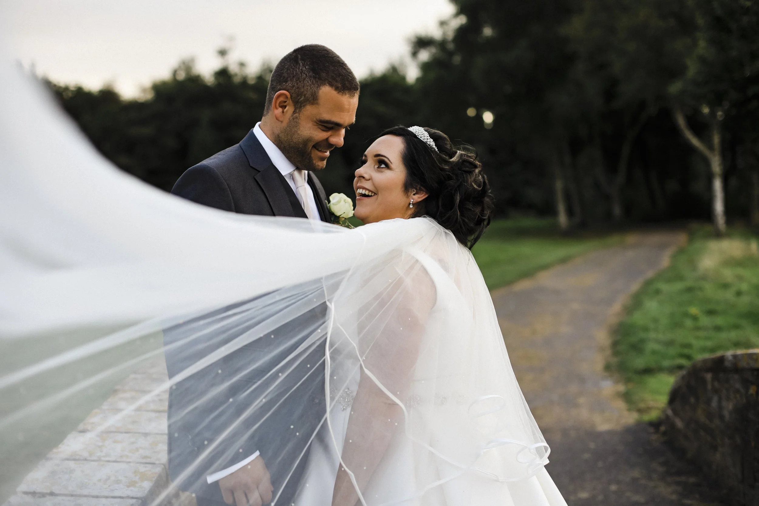 Bride and Groom's Exciting Gaze as Bride's Veil Sweeps Across Formby Hall Sefton Wedding Photography