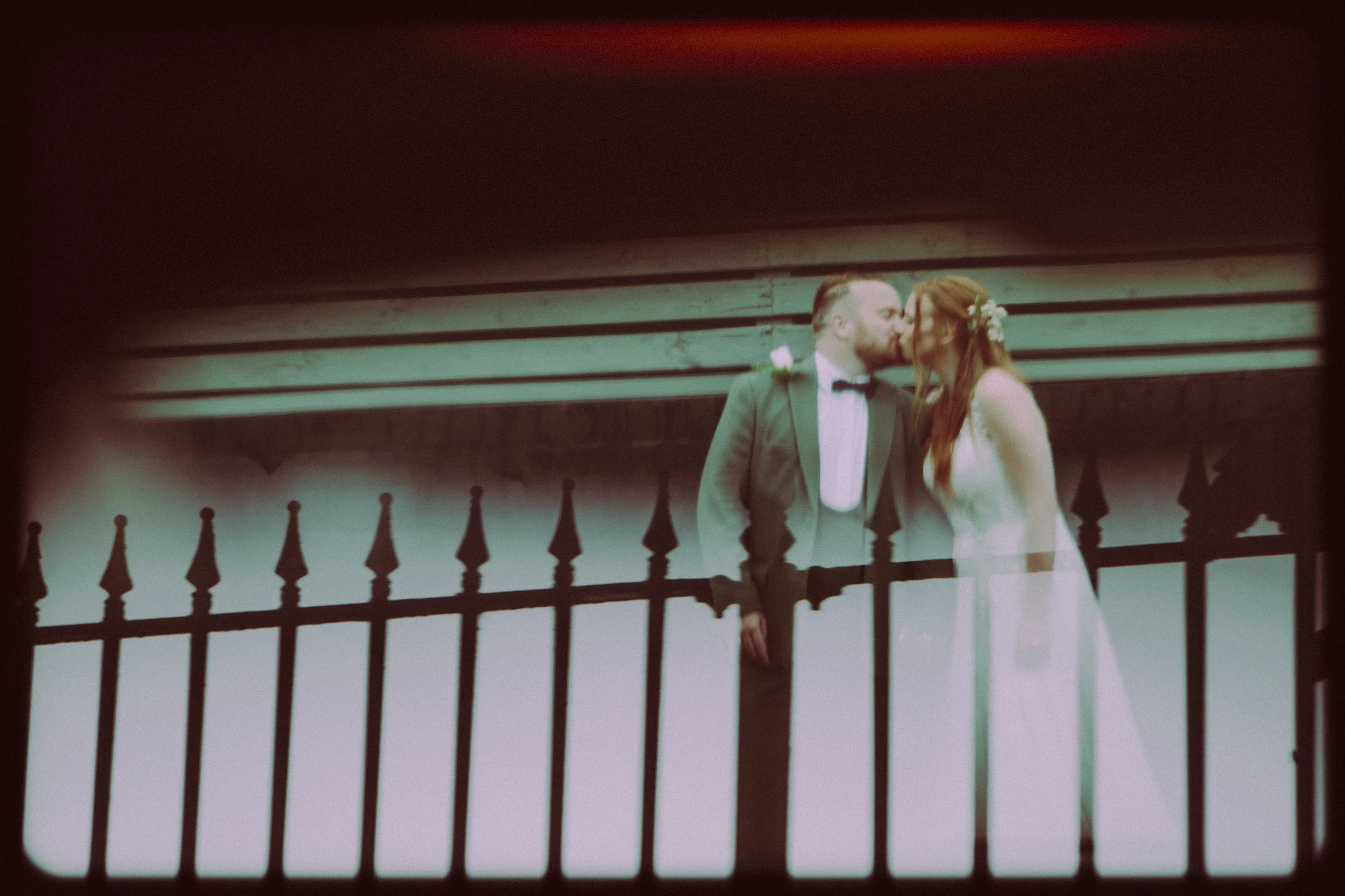 "Bride and groom's kiss, enhanced with cinematic edits, creates a captivating scene with reflections, adding a film-like allure to the moment