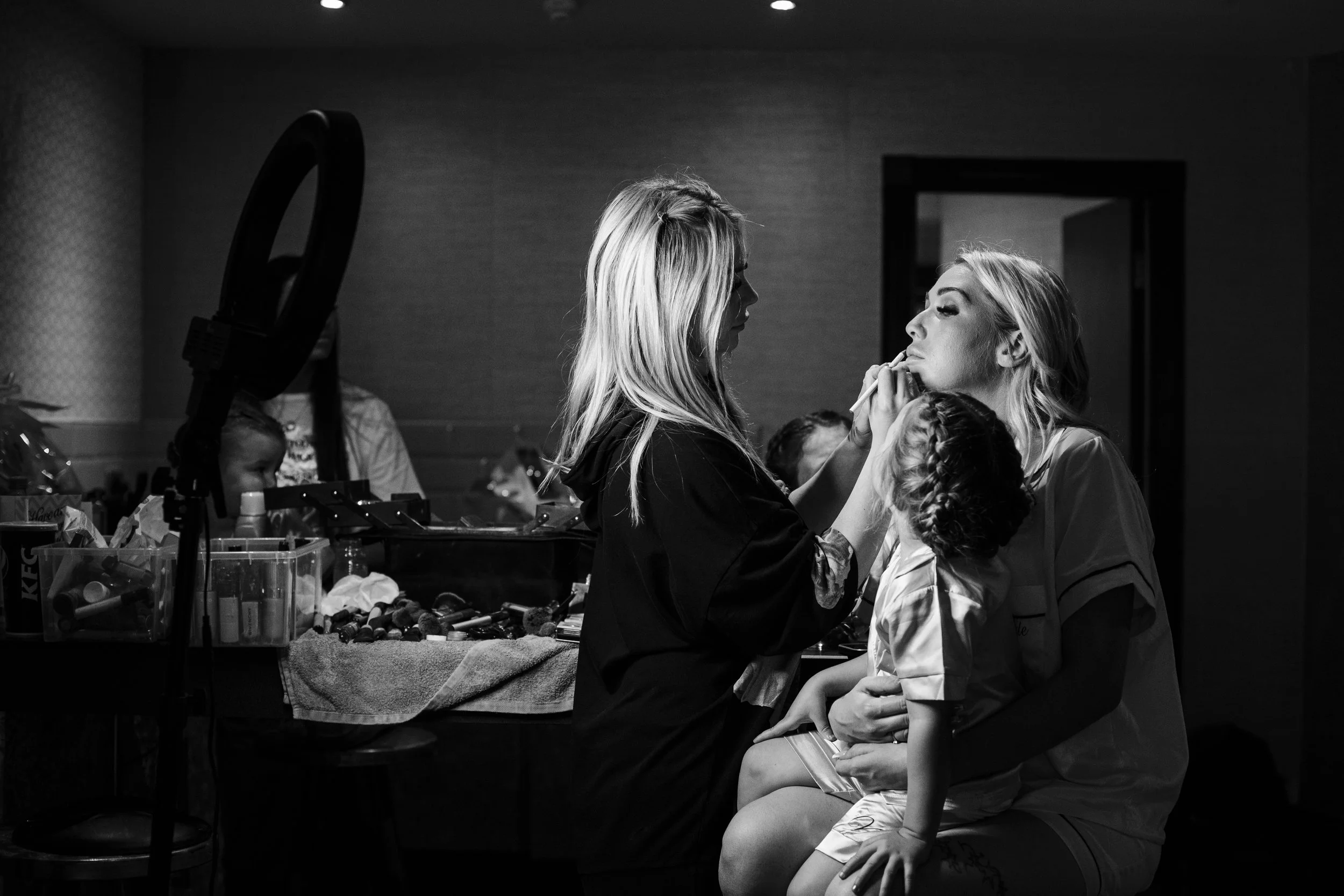 bride holding young daughter while getting her make up done at the Shankly Hotel  Liverpool wedding photography