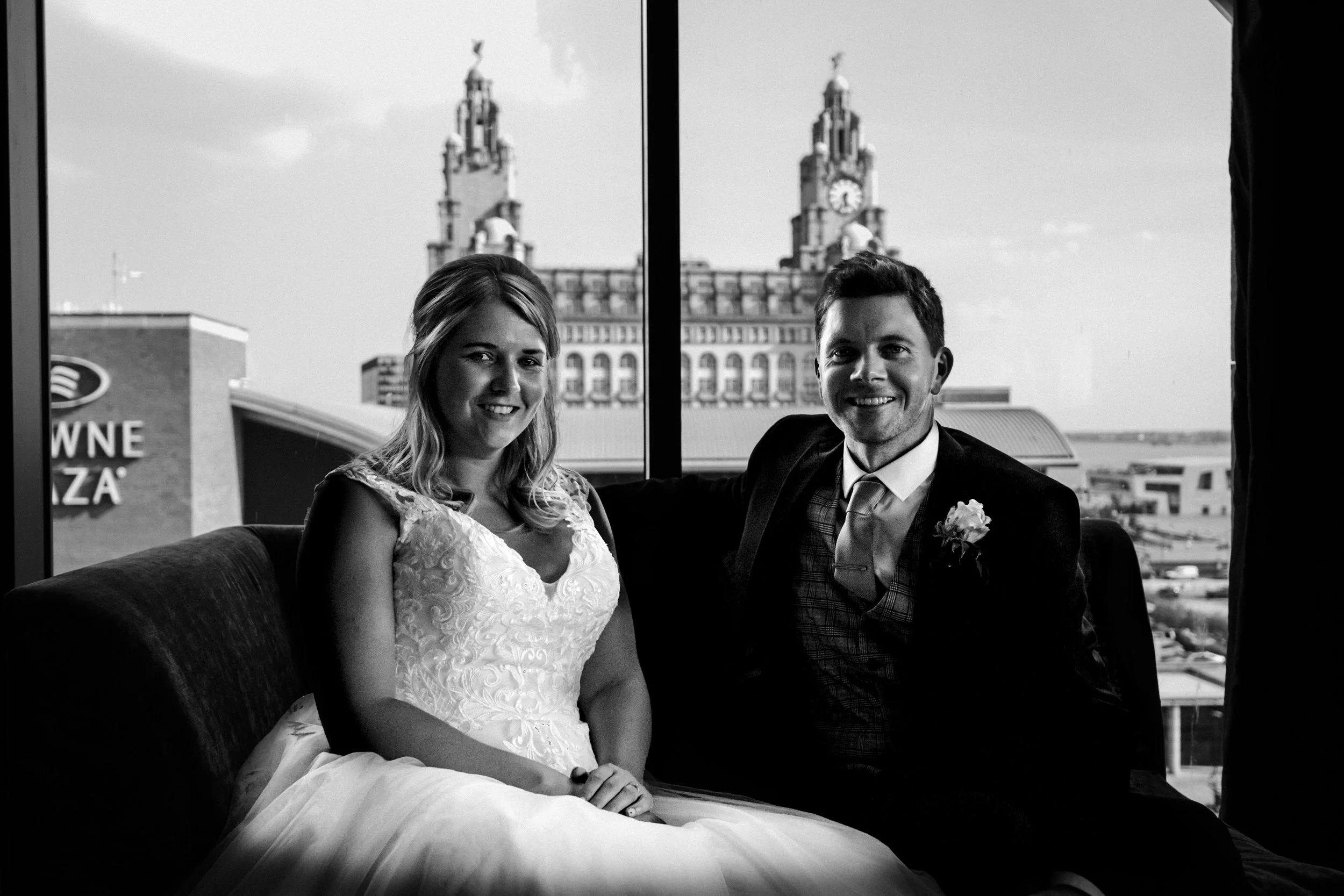 bride and groom in their room at the Malmaison hotel at Liverpool's Princes Dock with Liverpool's iconic liver buildings in the background  Liverpool wedding photography