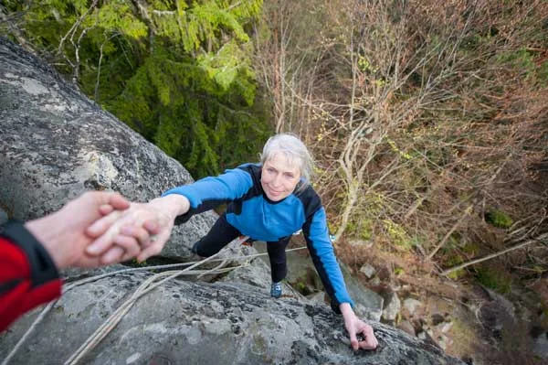 Male-rockclimber-is-helping-a-climber-female-to-reach-a-peak-of-mountain.jpg