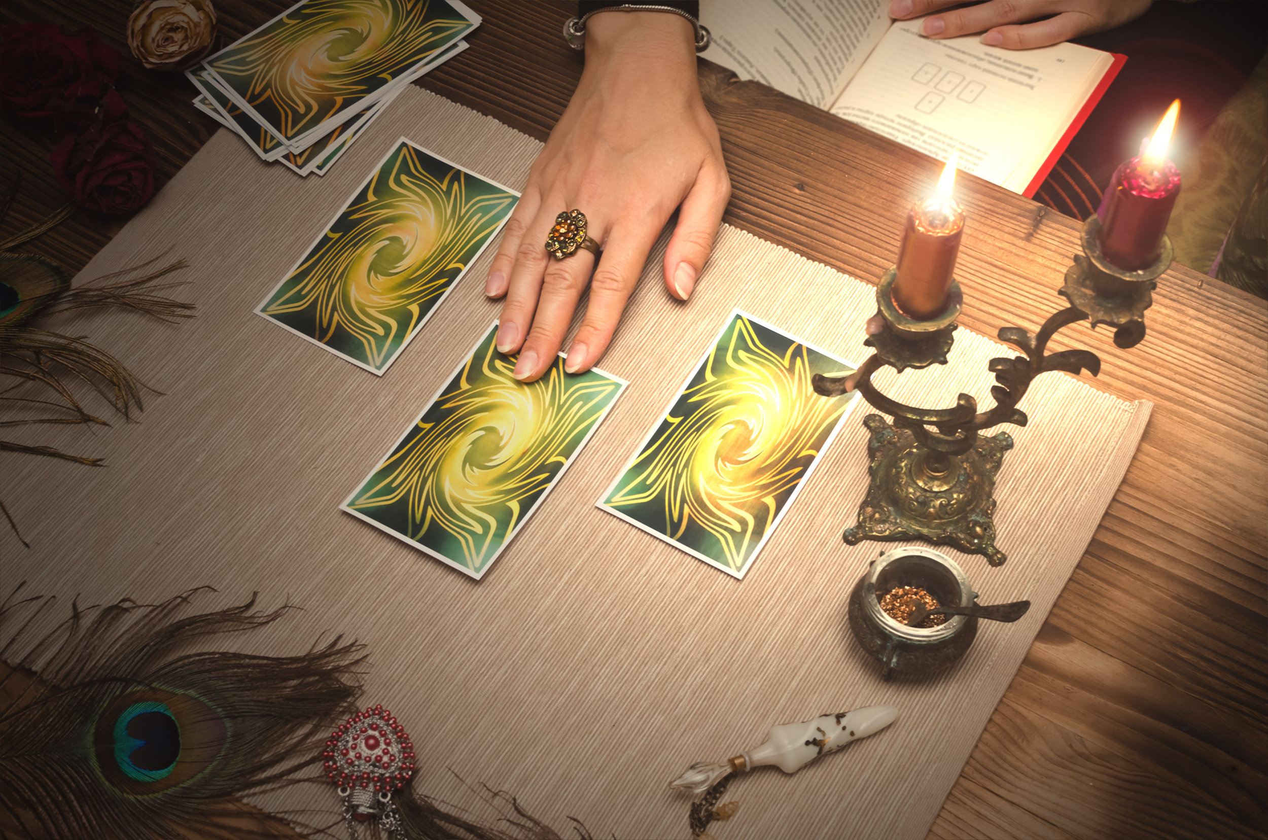 Tarot cards on wooden table, fortune teller hands and open book. Learning magic.