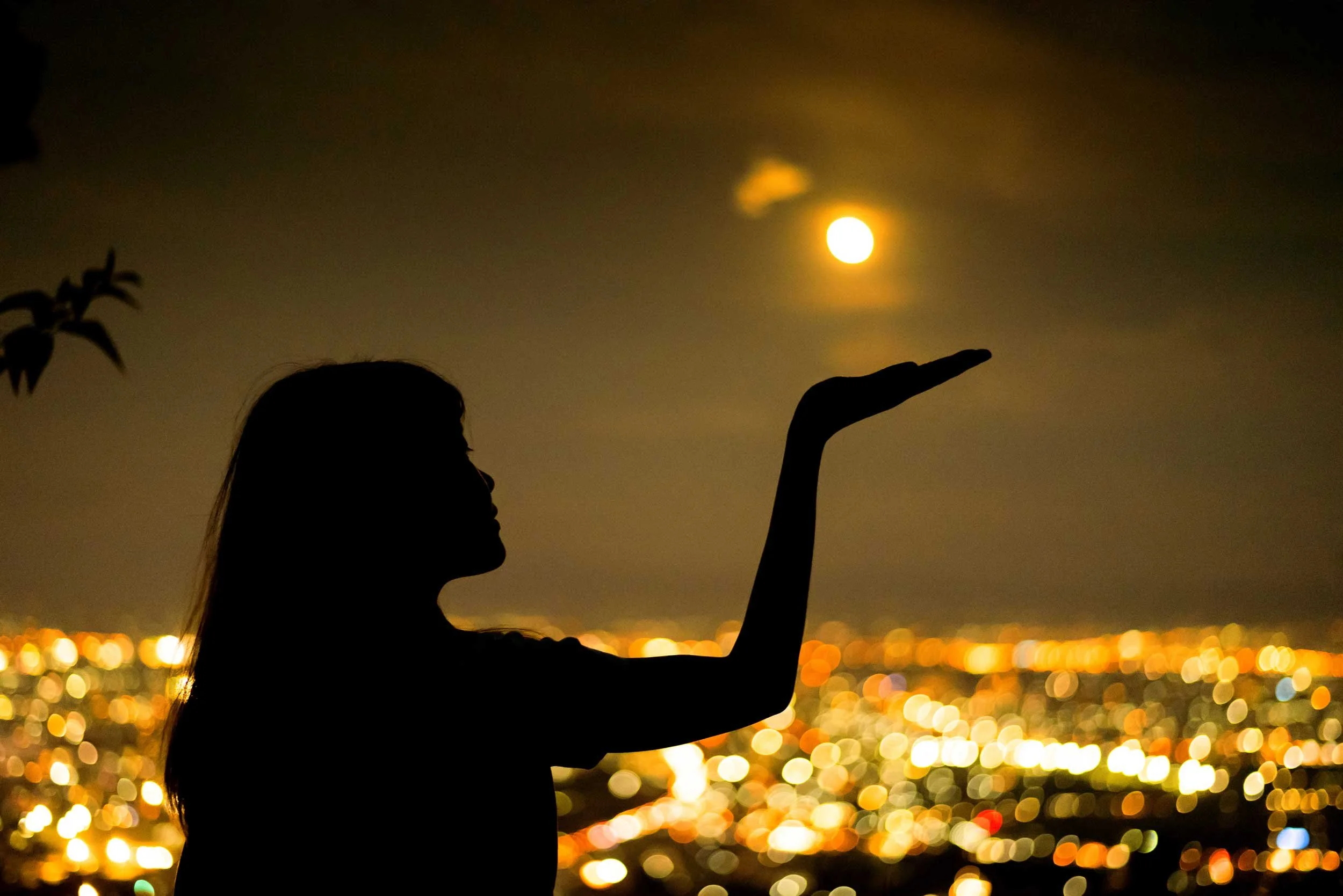 A woman on Earth plays with the Moon.