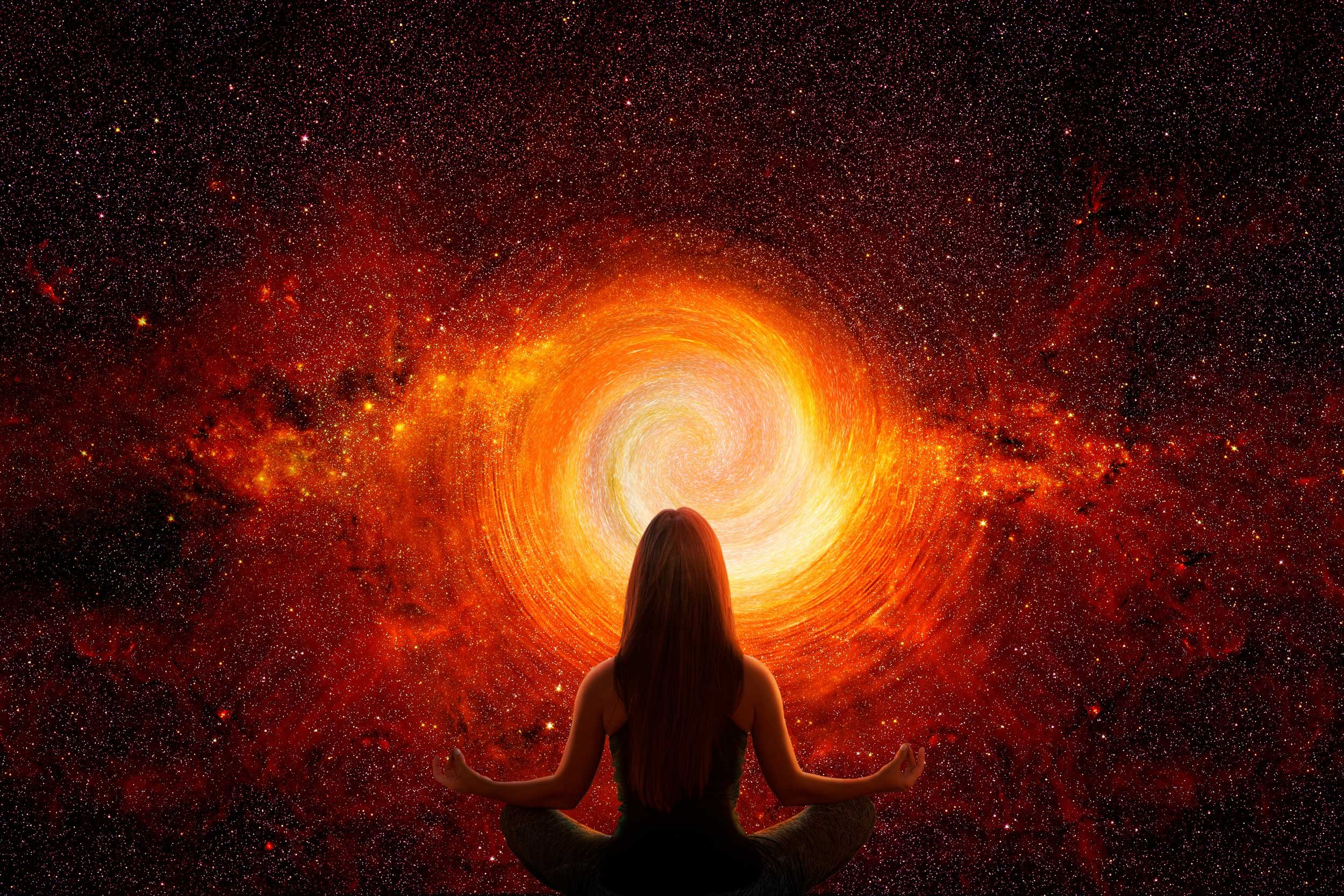 A woman meditates in front of a circle of fire.