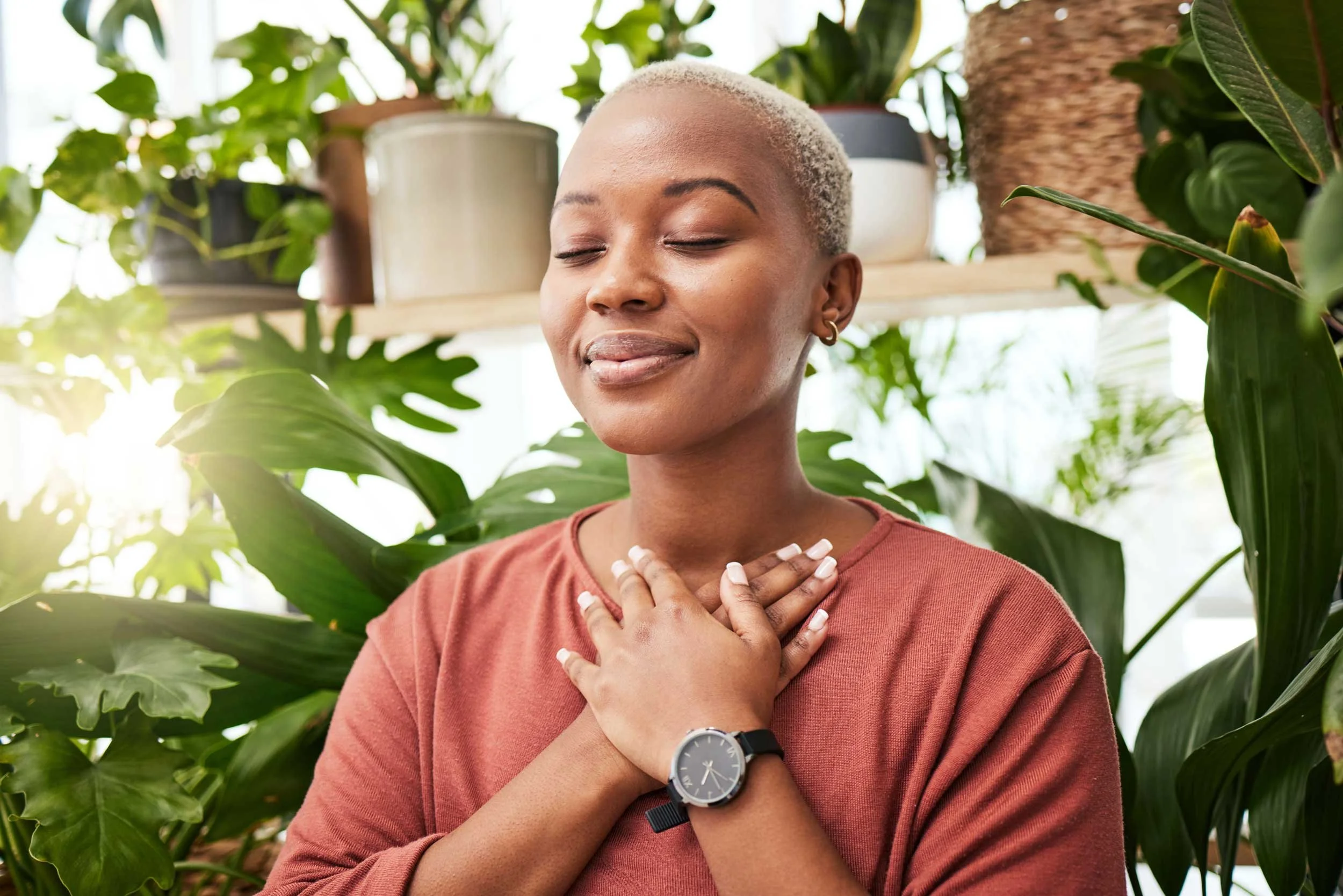 A woman meditating with her plants.