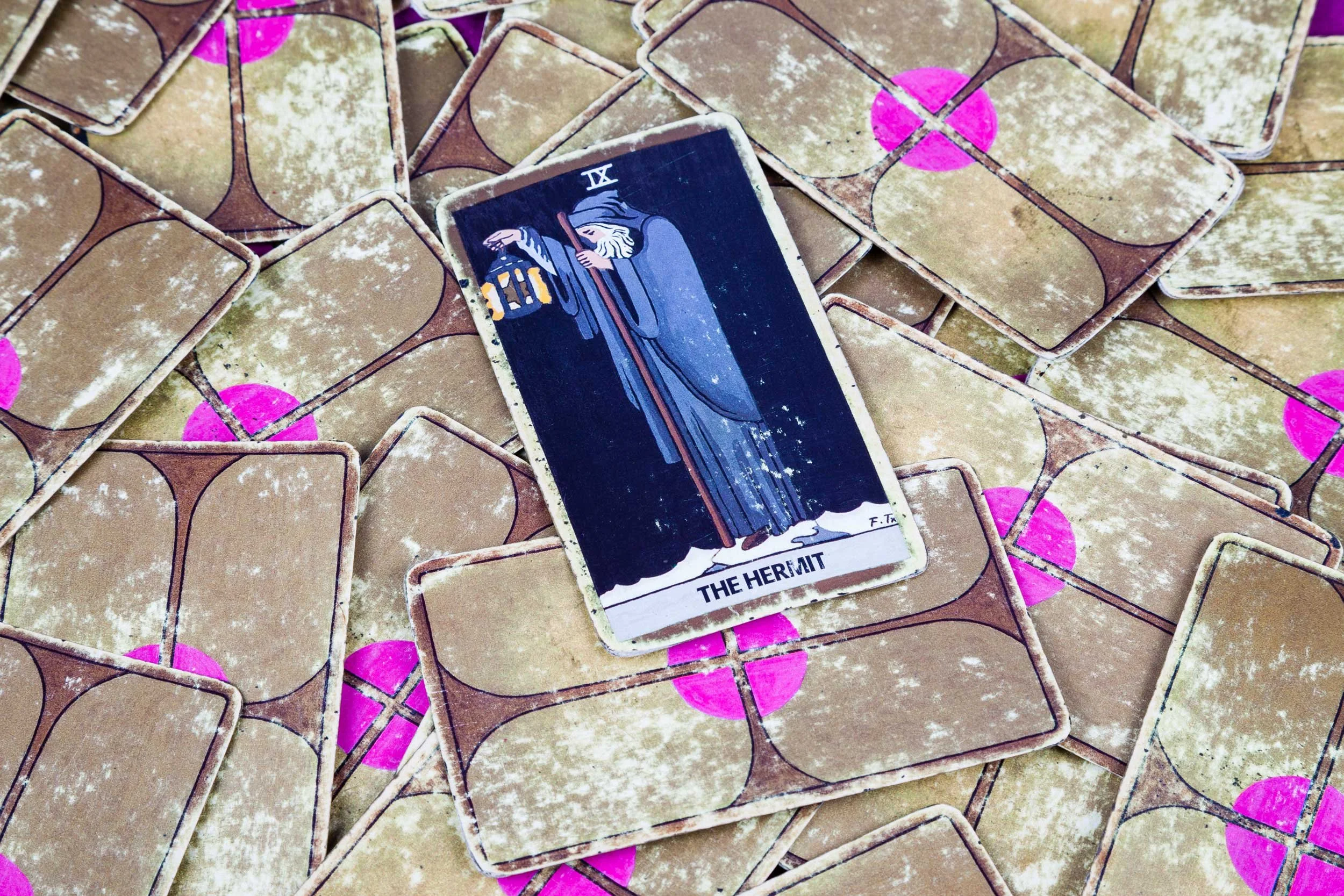 The Hermit tarot card on a pile of tarot cards.