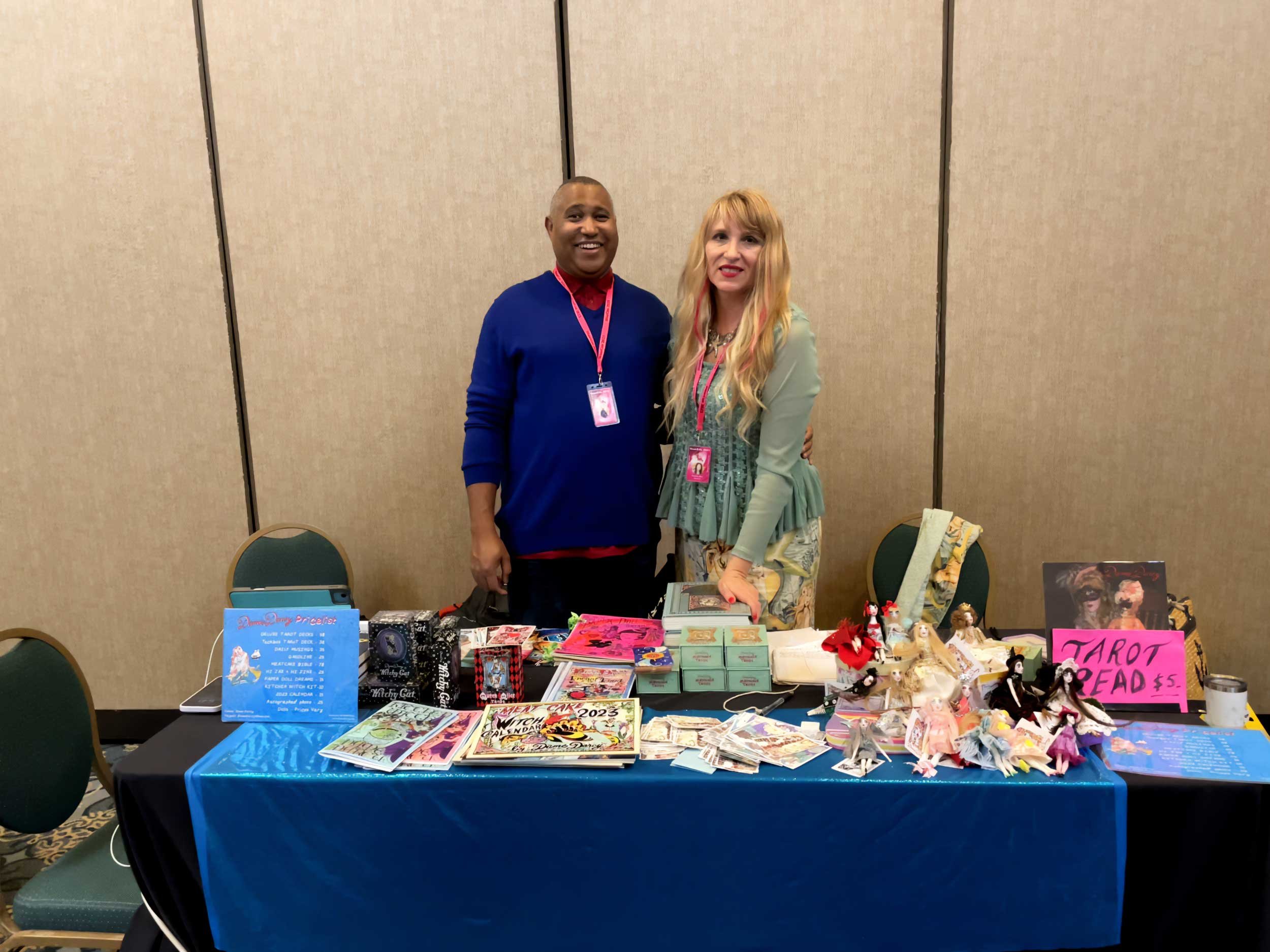 Dame Darcy and Pleasant stand behind their vending table at StaarCon.