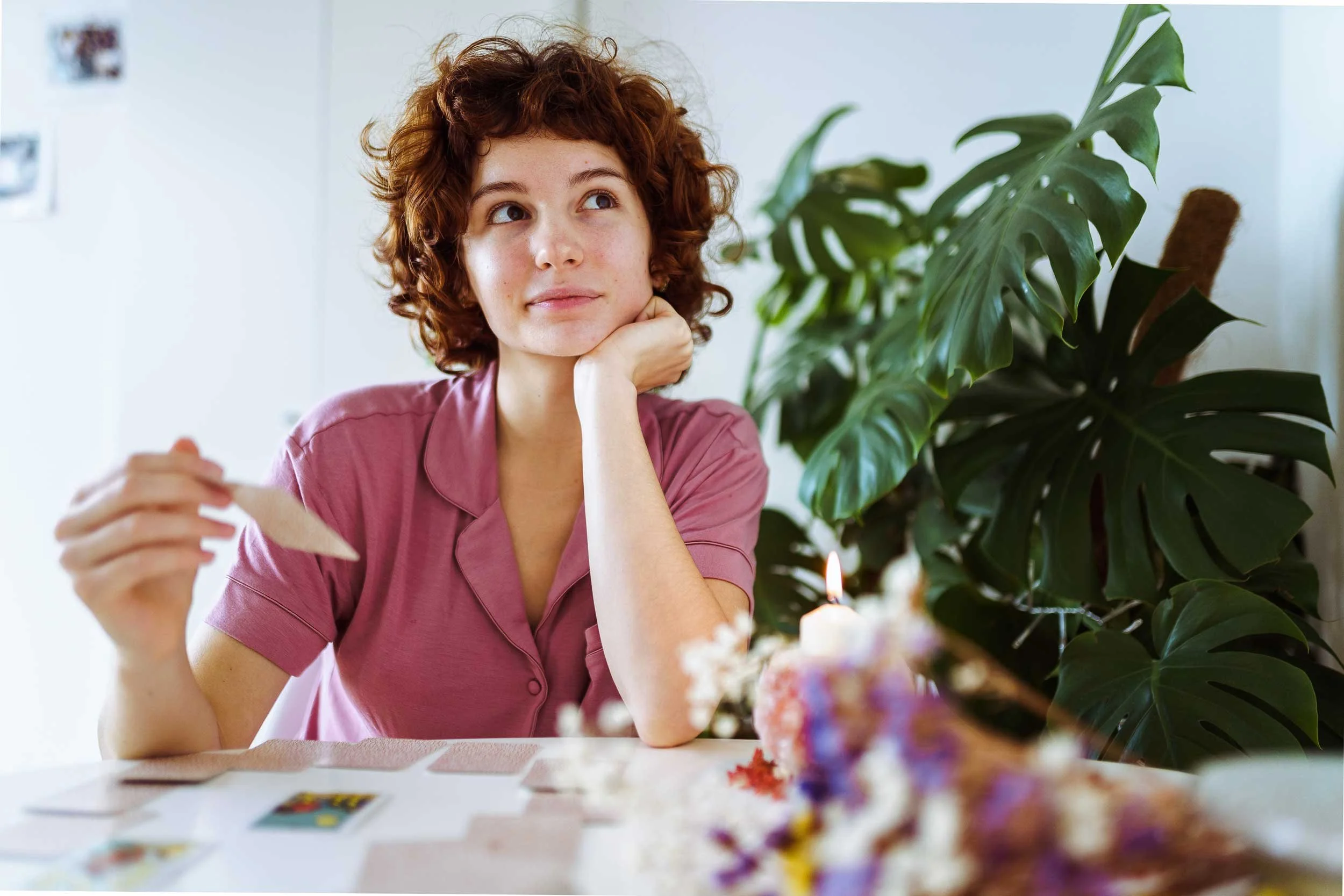 A woman contemplates a tarot card.