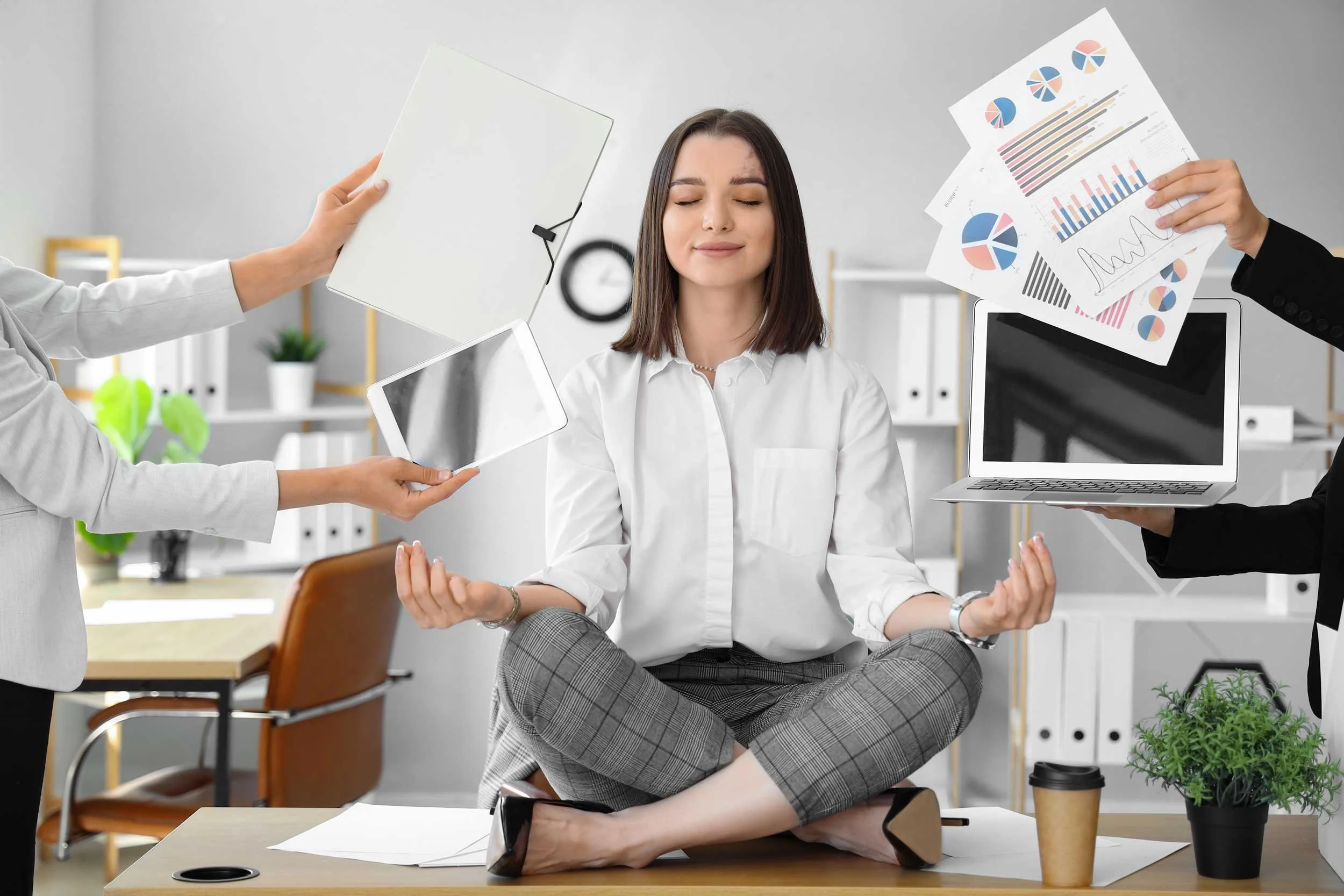 A woman meditates in a busy office.