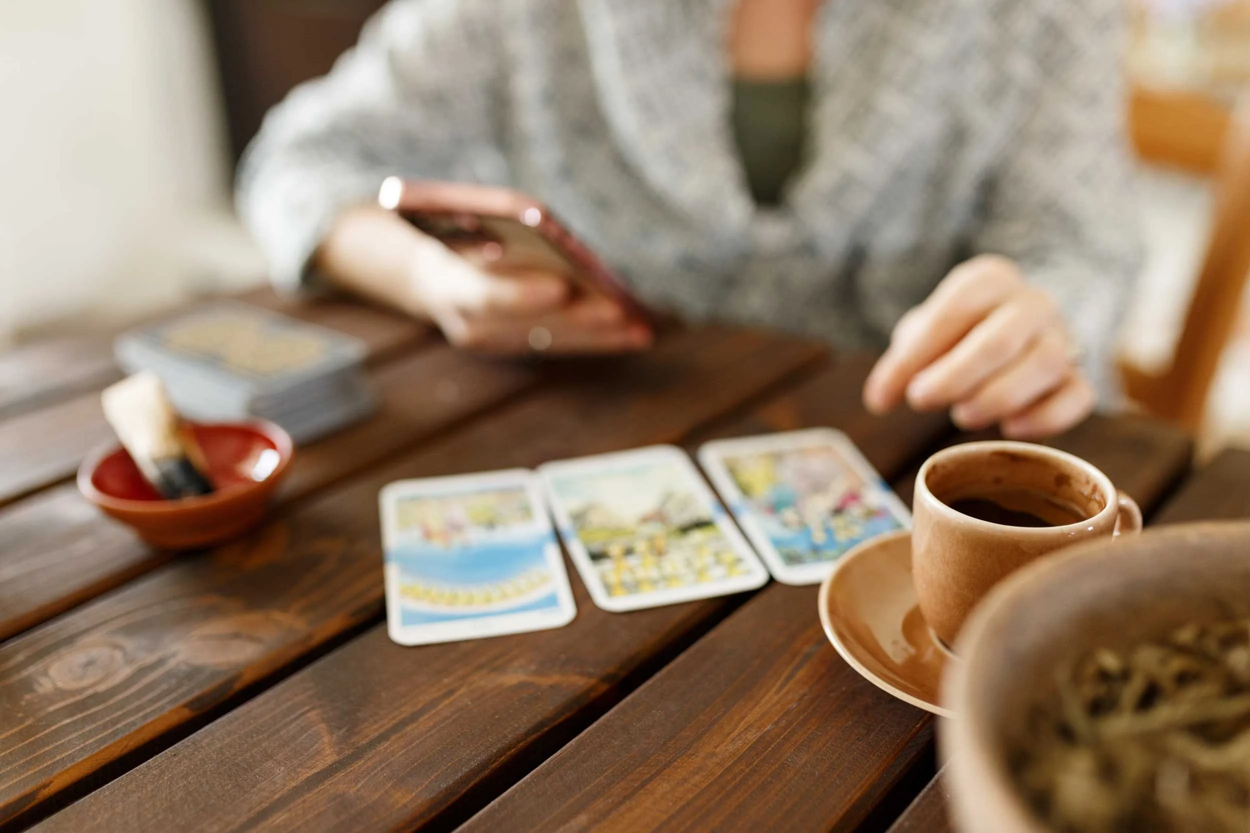 A woman consults her phone and her tarot cards.