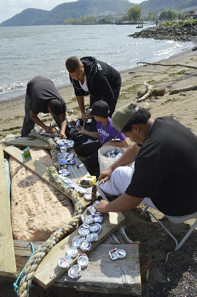 Productive kids building a raft from plank and crushed cans for the "bird" sculpture to take a ride on the river.