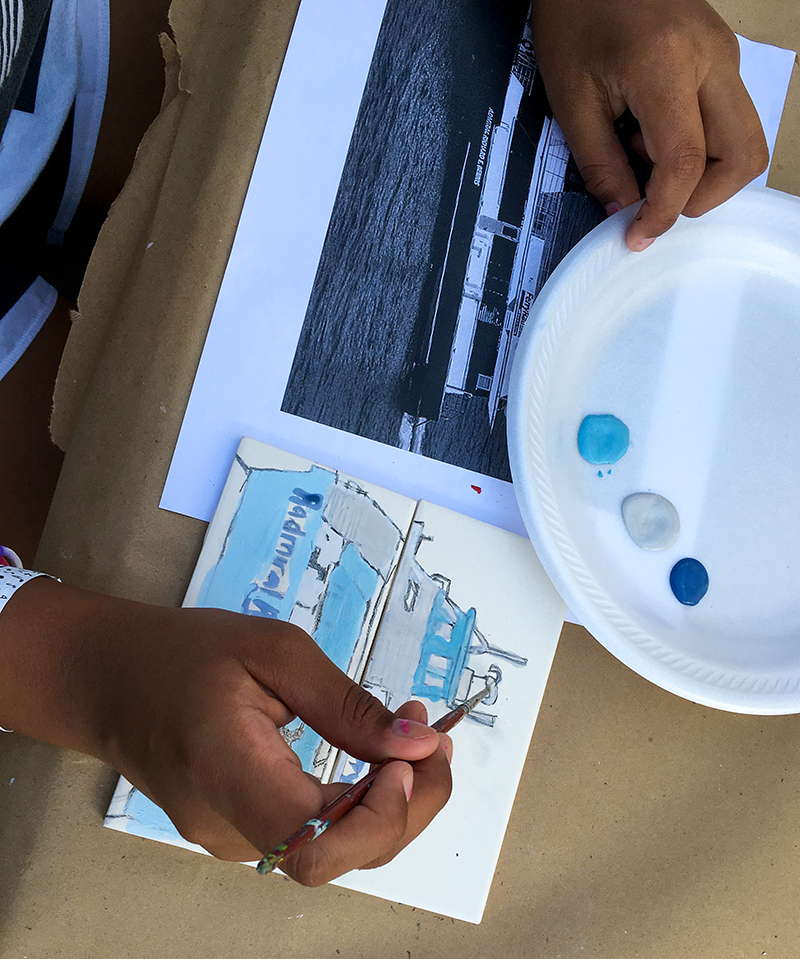 Participant painting a tile of a ship in the Community Tile Project
