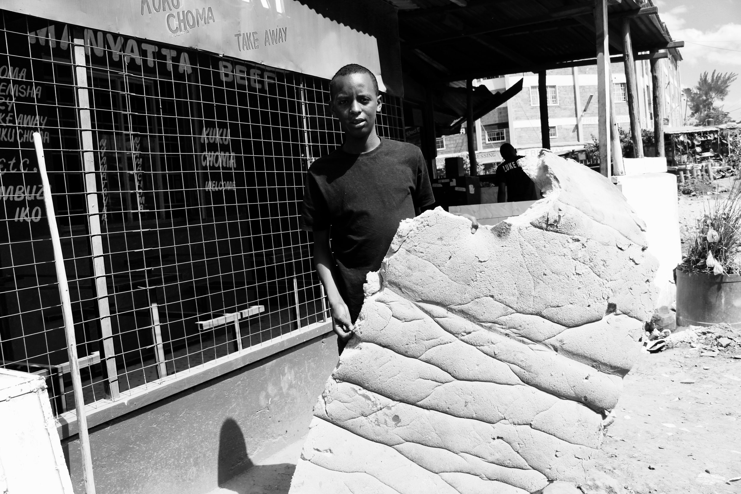 Boniface holding up a mattress the boys sleep on at night.