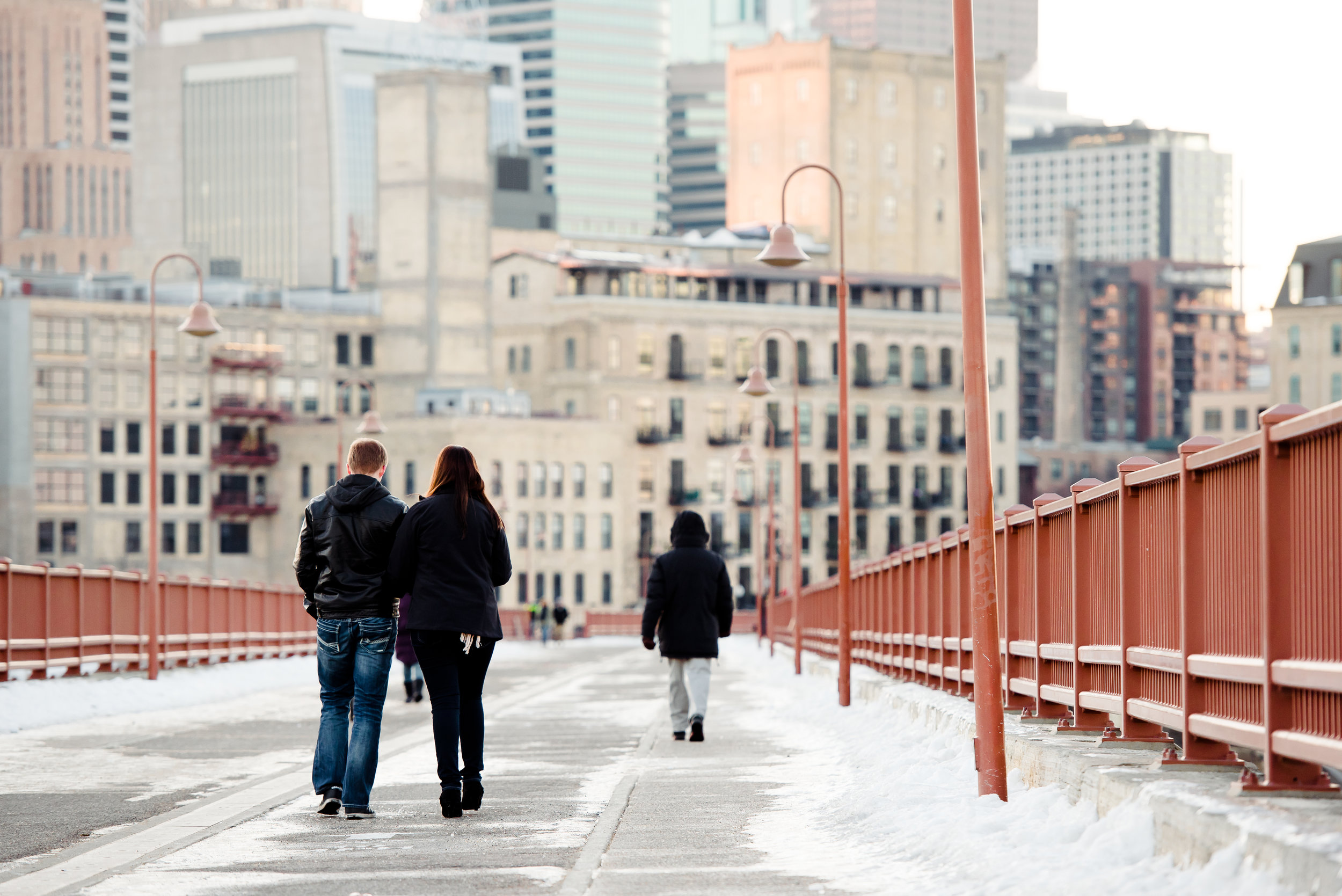 Stone Arch Bridge Proposal - Couple Walking at Sunset in the Winter Snow - MPLS Engagement Proposal Photography