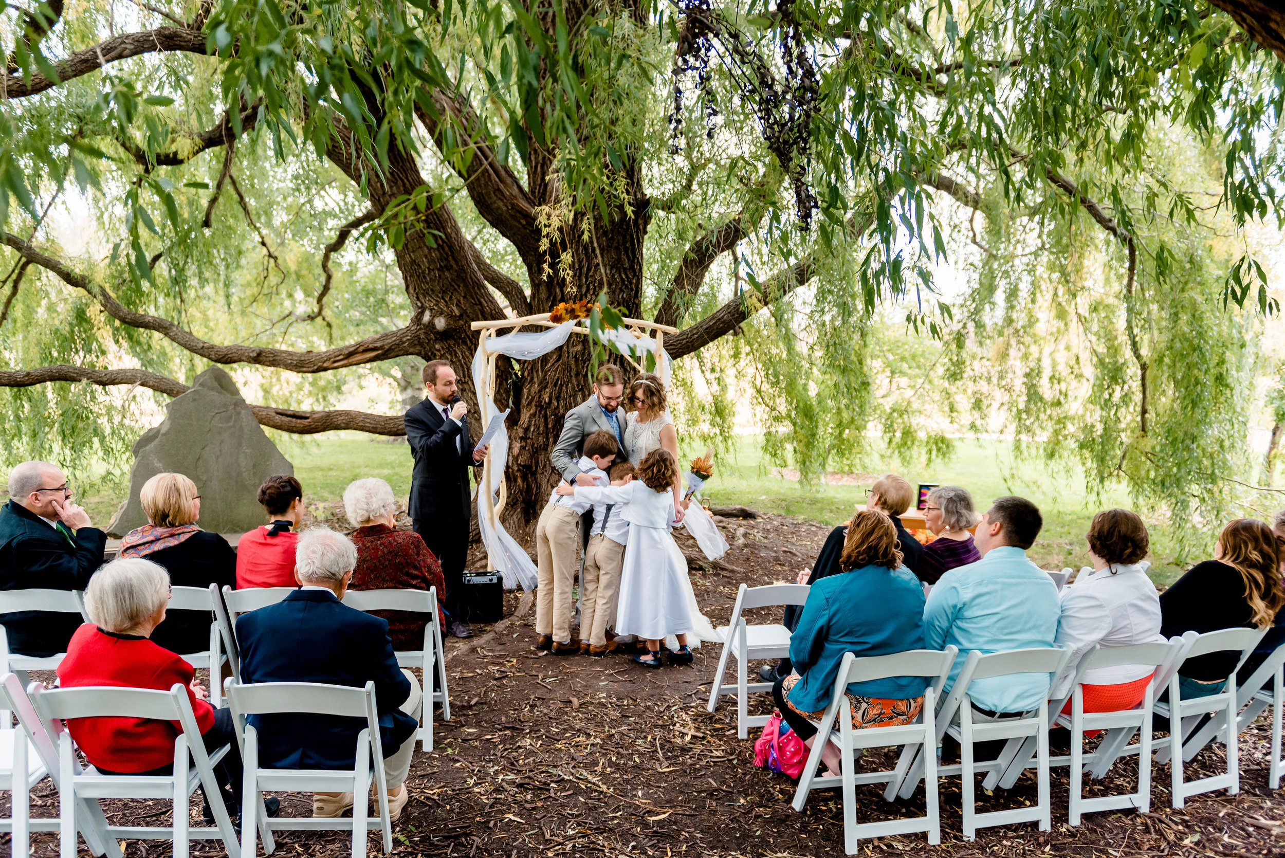 Ceremony Kiss at Weeping Willow Trees Ceremony Site at MN Landscape Arboretum - Fall Wedding - Minneapolis area Wedding Photographer