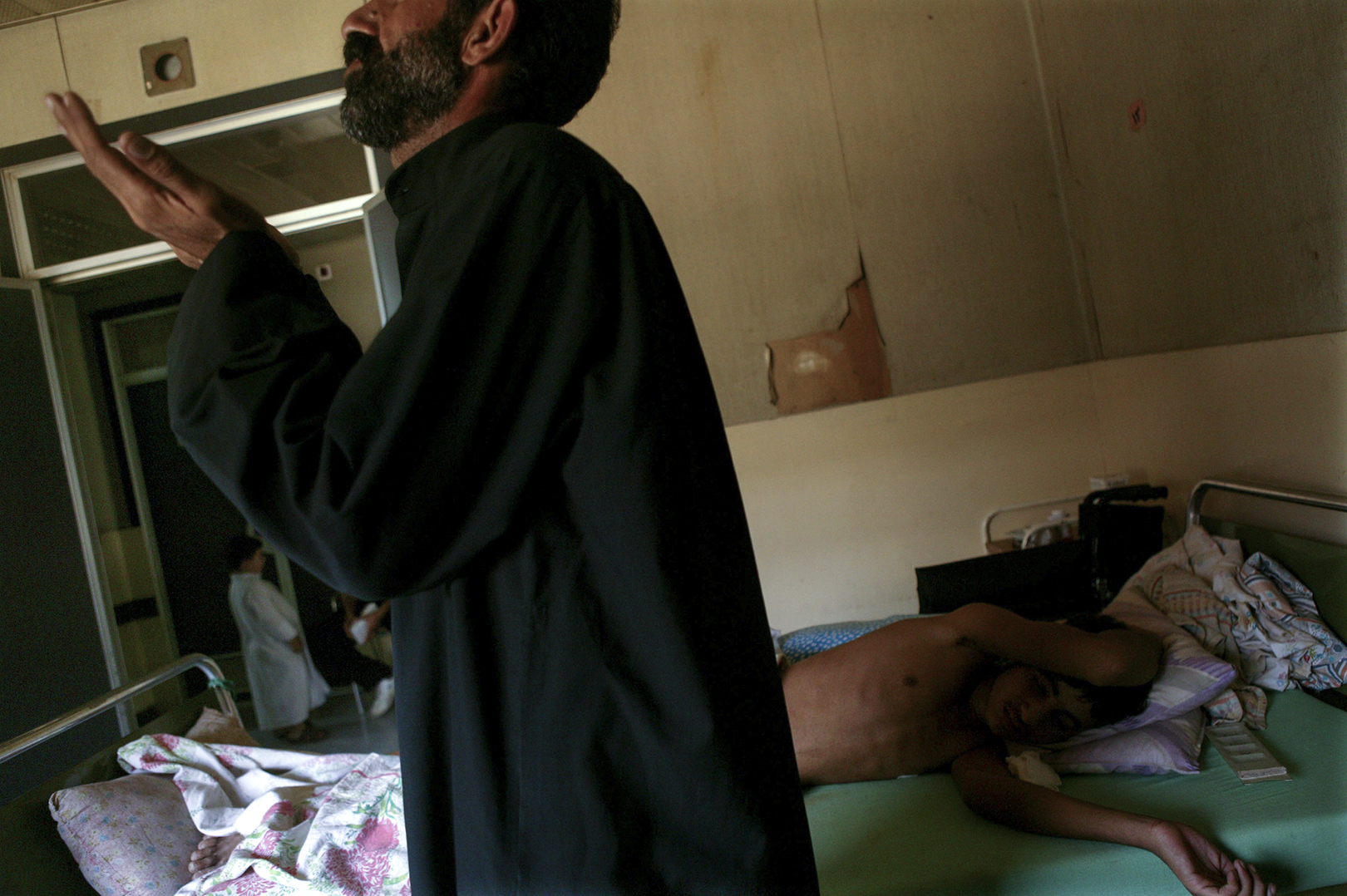  A father prays for his son in their hospital room. 