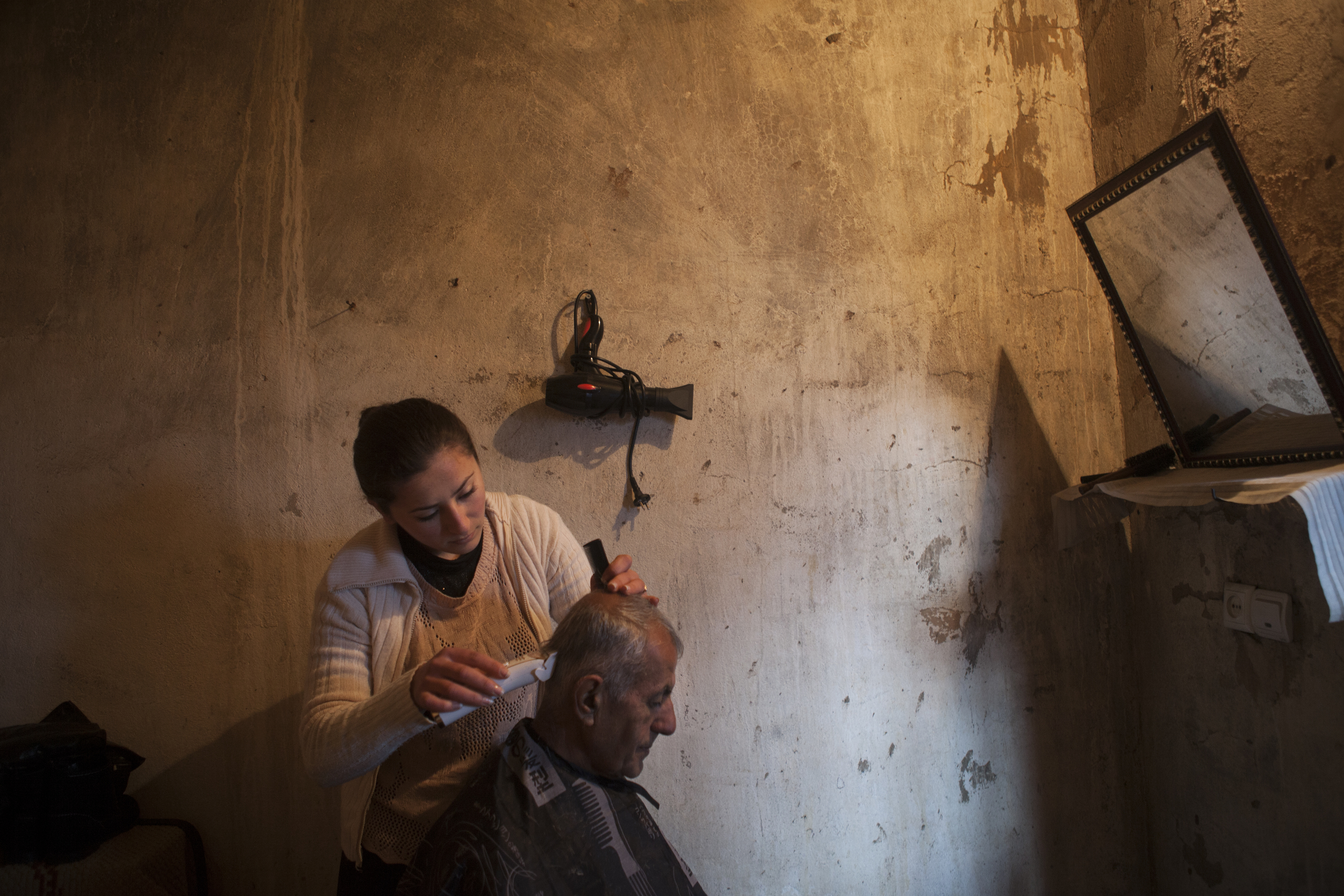  A displaced Syrian-Armenian gets his hair cut at a local's home turned makeshift barber shop. 