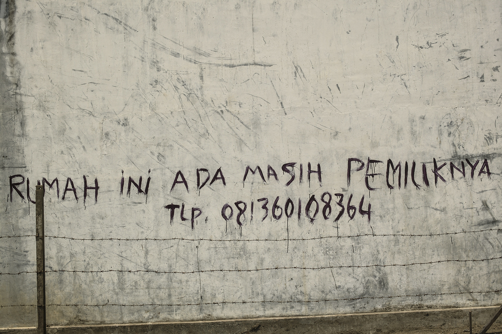  “Owner of this house still alive,” reads a message written on the side of a&nbsp;house. 