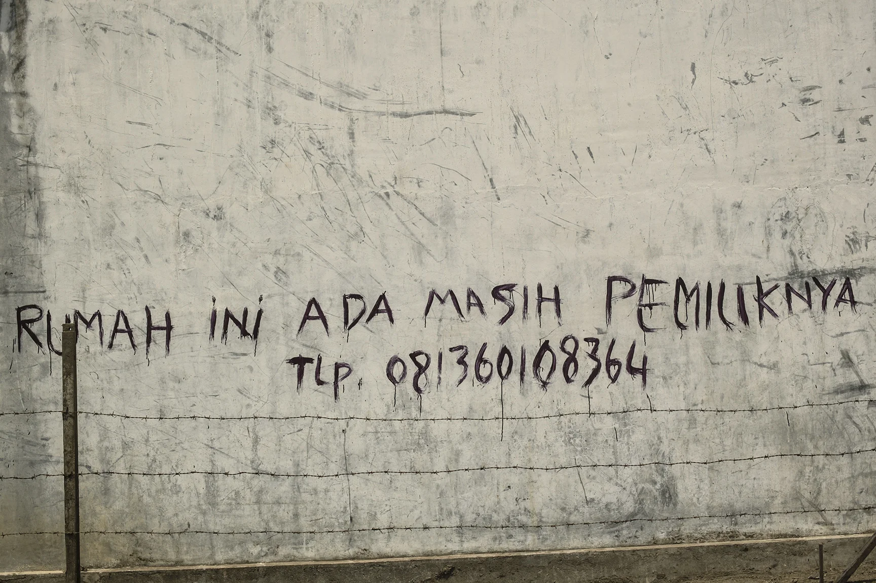 “Owner of this house still alive,” reads a message written on the side of a house.