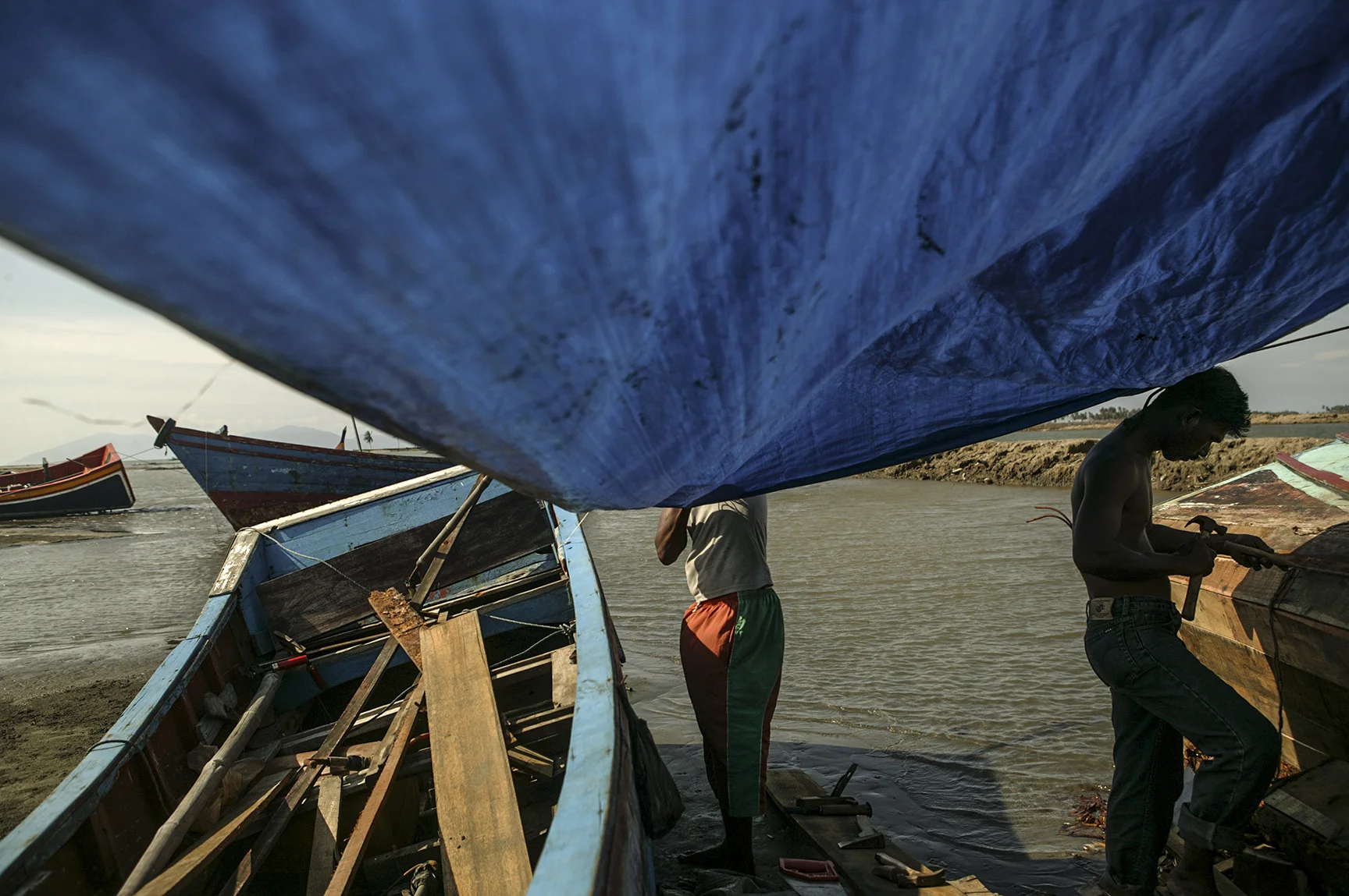 Locals of a fishing community repair their boats.