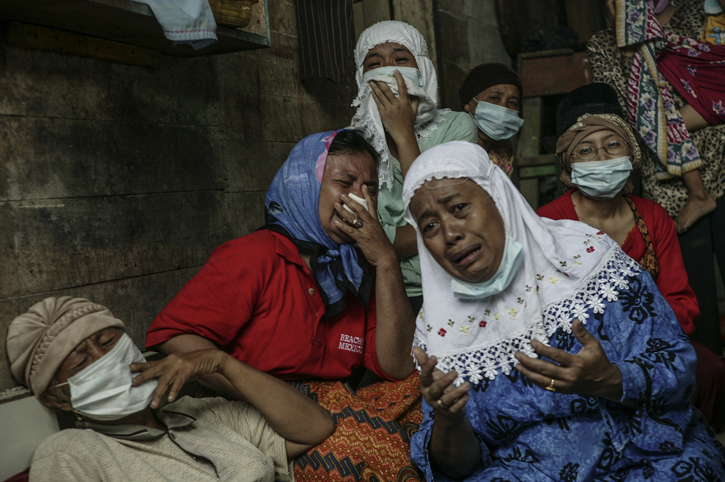 A family grieves as a deceased family member is extracted from the collapsed section of their home.