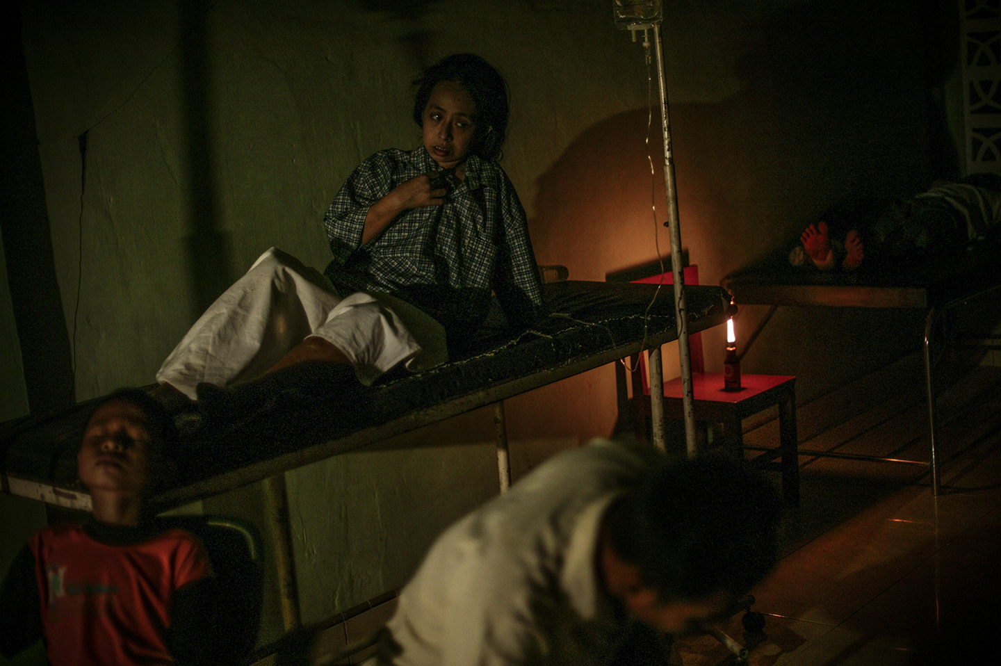Injured survivors by candlelight at the city's local hospital. The hospital ran without electricity for the first three days after the earthquake. Most of the hospital rooms were destroyed so patients were treated in the lobby area.
