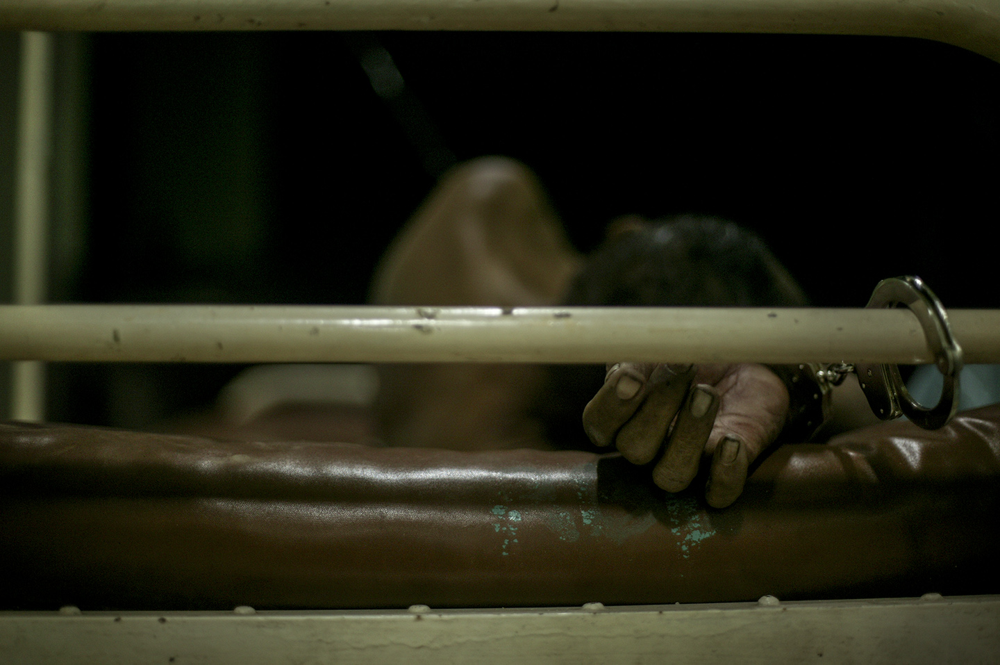 An injured man is cuffed to a hospital bed. 