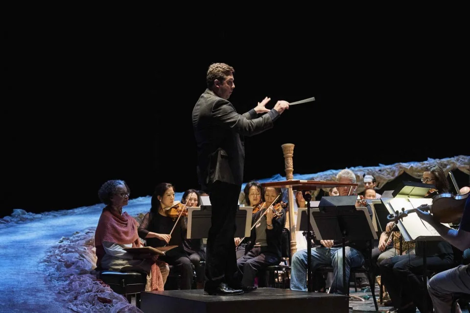 Cleveland Orchestra associate conductor Brett Mitchell (pictured here in a dress rehearsal) presided over performances of works by Britten and Adams that formed the musical backbone of "The Good Peaches," a new play by Quiara Alegría Hudes premiered…