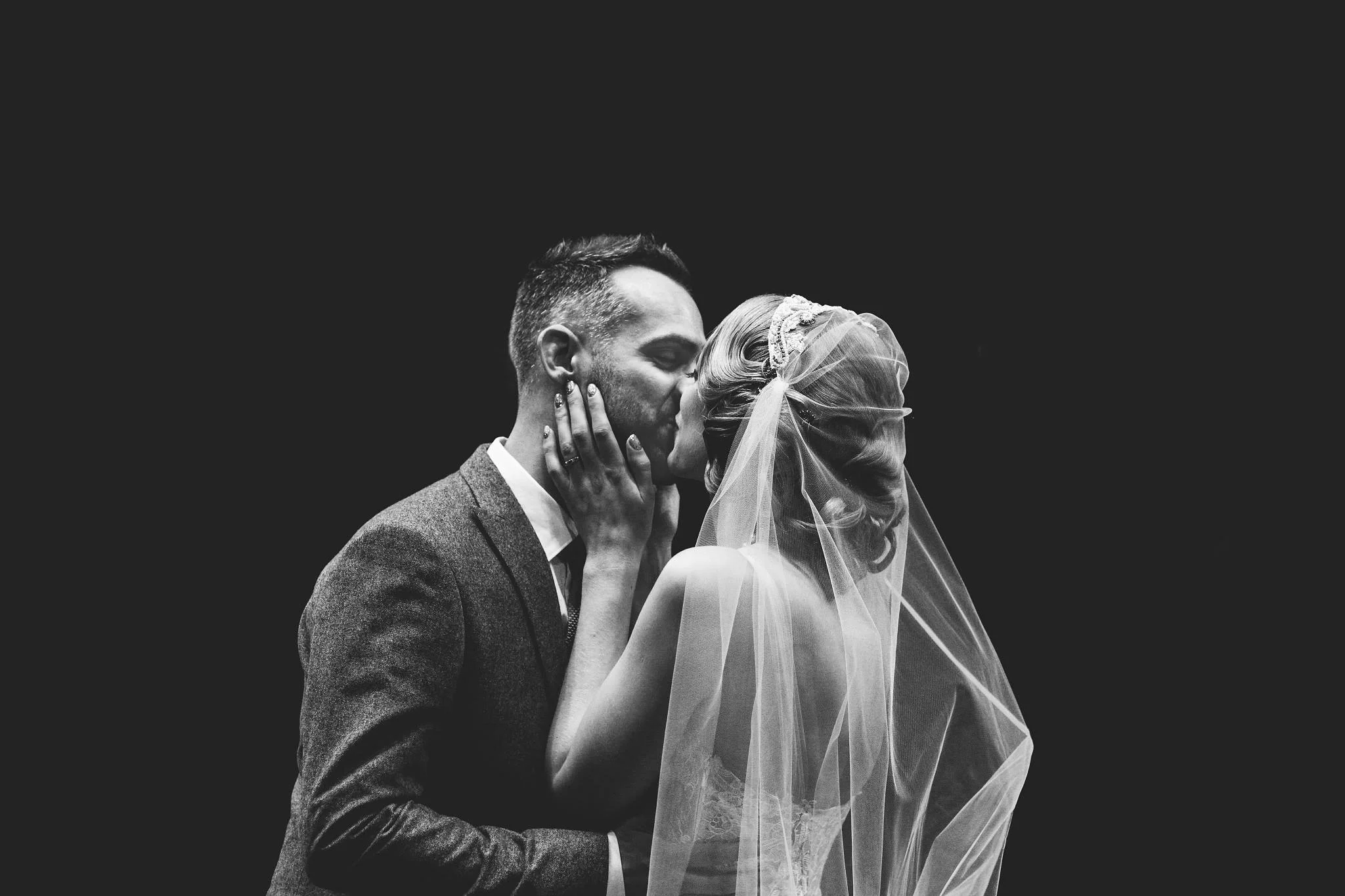 Black and white photo of bride and groom kissing